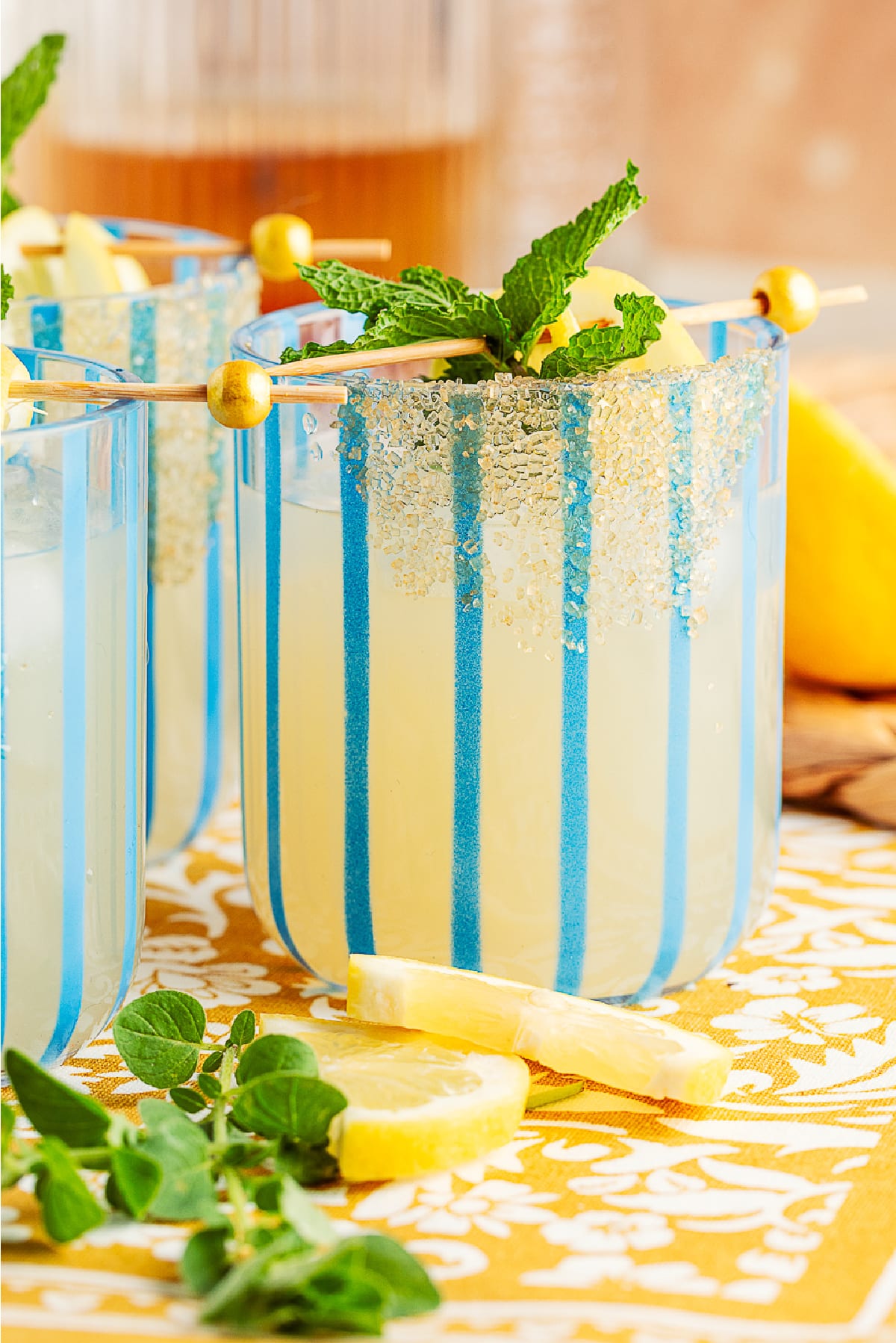 Vibrant gin smash with lemon and mint on a blue plate, surrounded by oregano and lemon wedges.