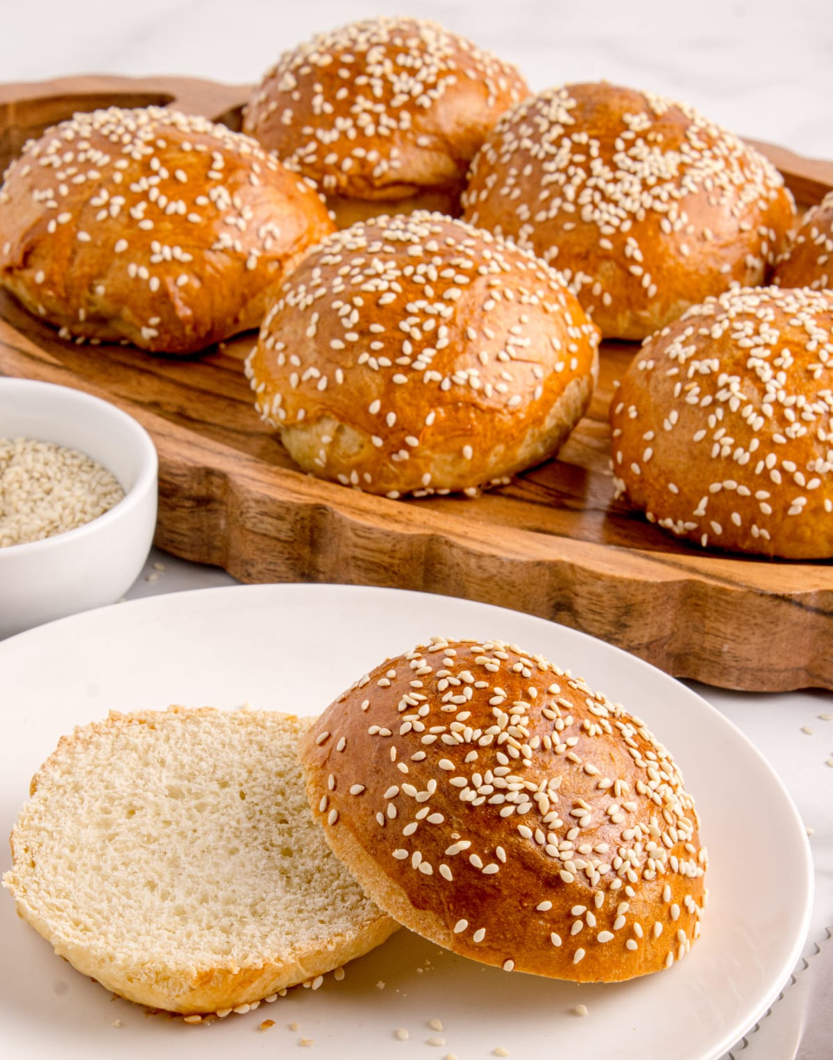 Soft slider buns with sesame seed topping Close up of sesame seed slider buns cooling on a wooden platter