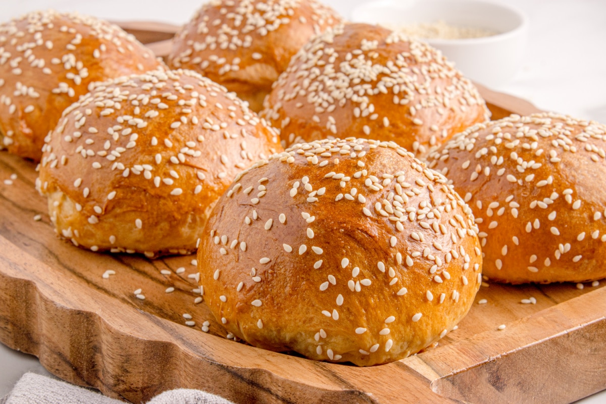 Soft slider buns with sesame seed topping Close up of sesame seed slider buns cooling on a wooden platter