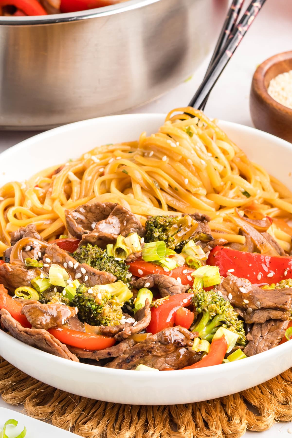 Noodles with teriyaki beef, broccoli, and peppers topped with sesame seeds