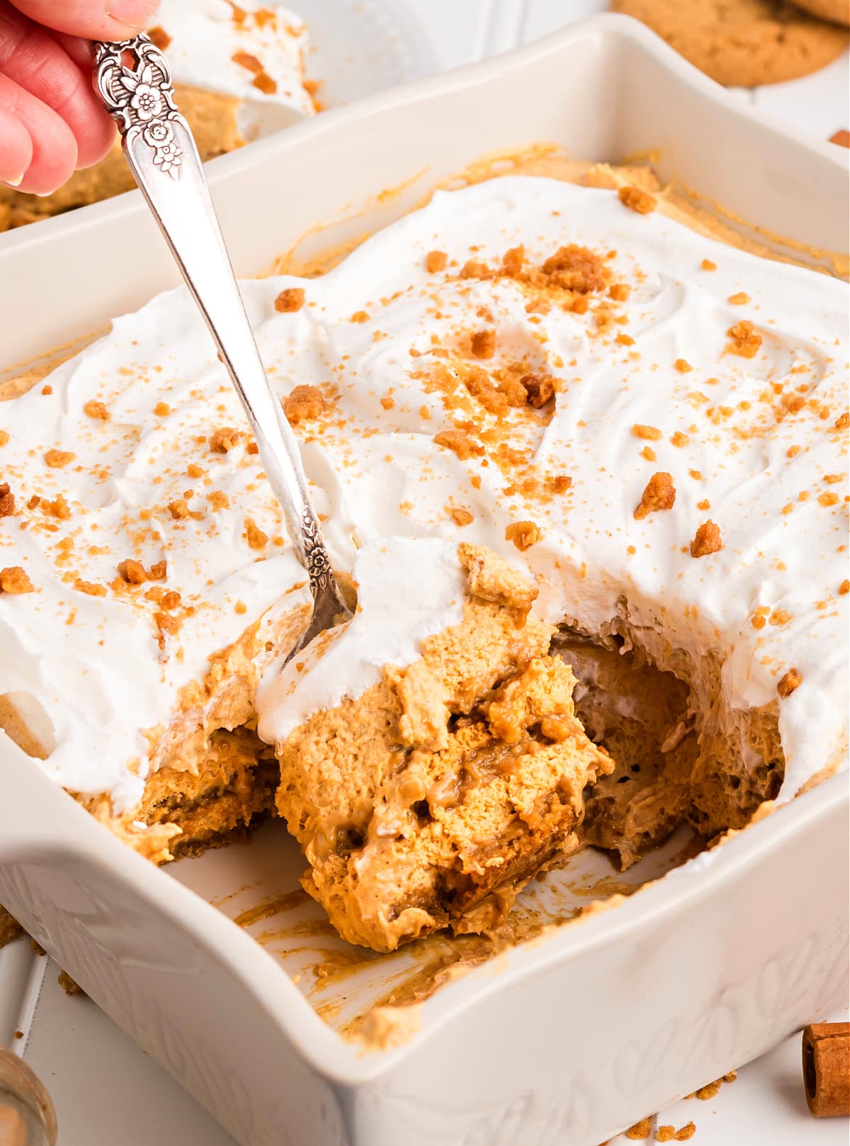 Pumpkin icebox cake in a baking dish with whipped topping and gingersnap crumbs