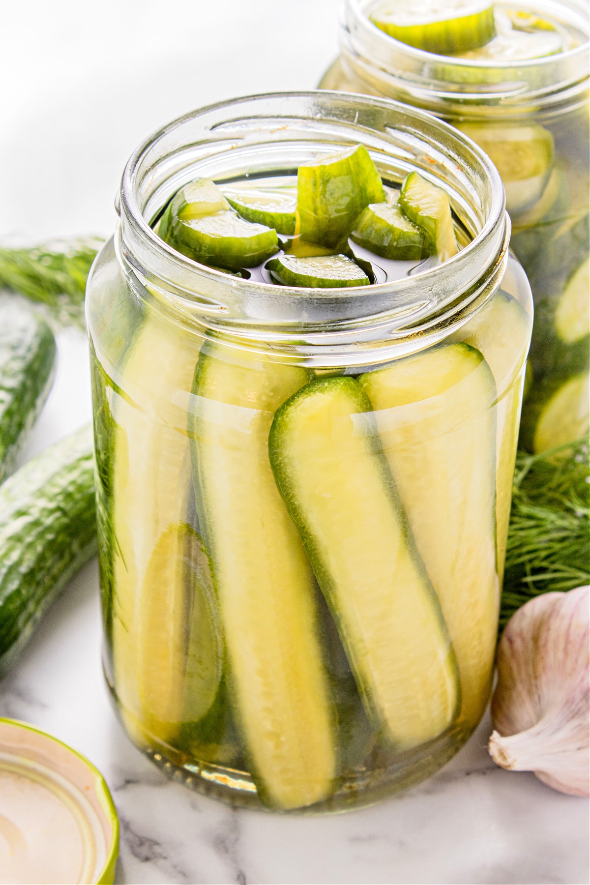 Refrigerator dill pickles packed into a glass jar with cucumber spears and coins.