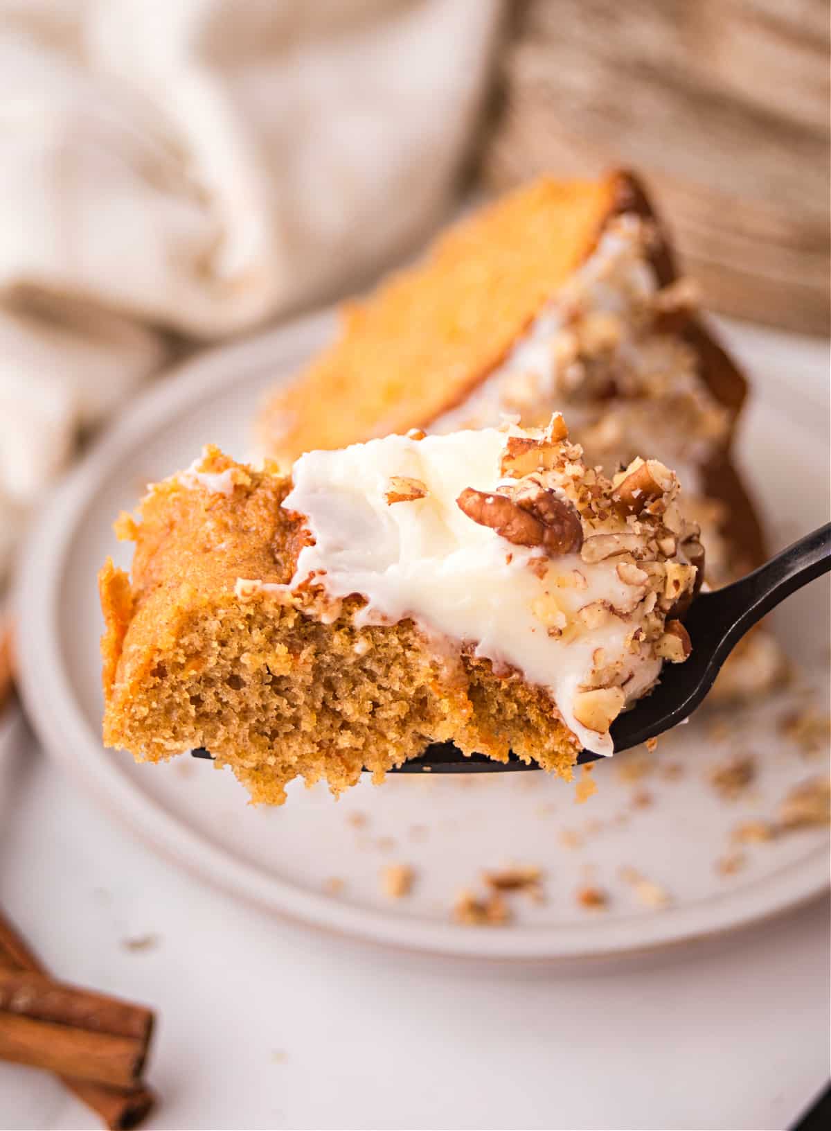 spiced carrot bundt cake bite Bite of spiced carrot bundt cake with cream cheese frosting on a fork.