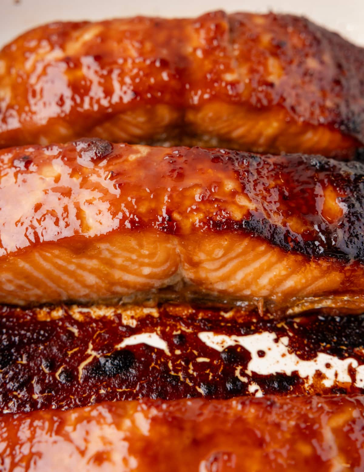 Close-up of miso glazed salmon fillets in the pan with a caramelized sticky glaze.