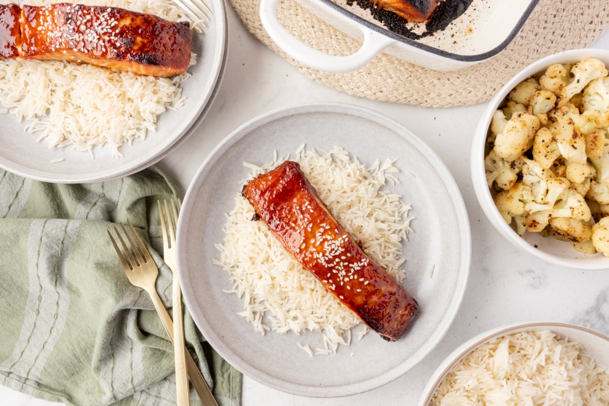 Dinner table with baked miso glazed salmon fillets on rice, served with roasted cauliflower.