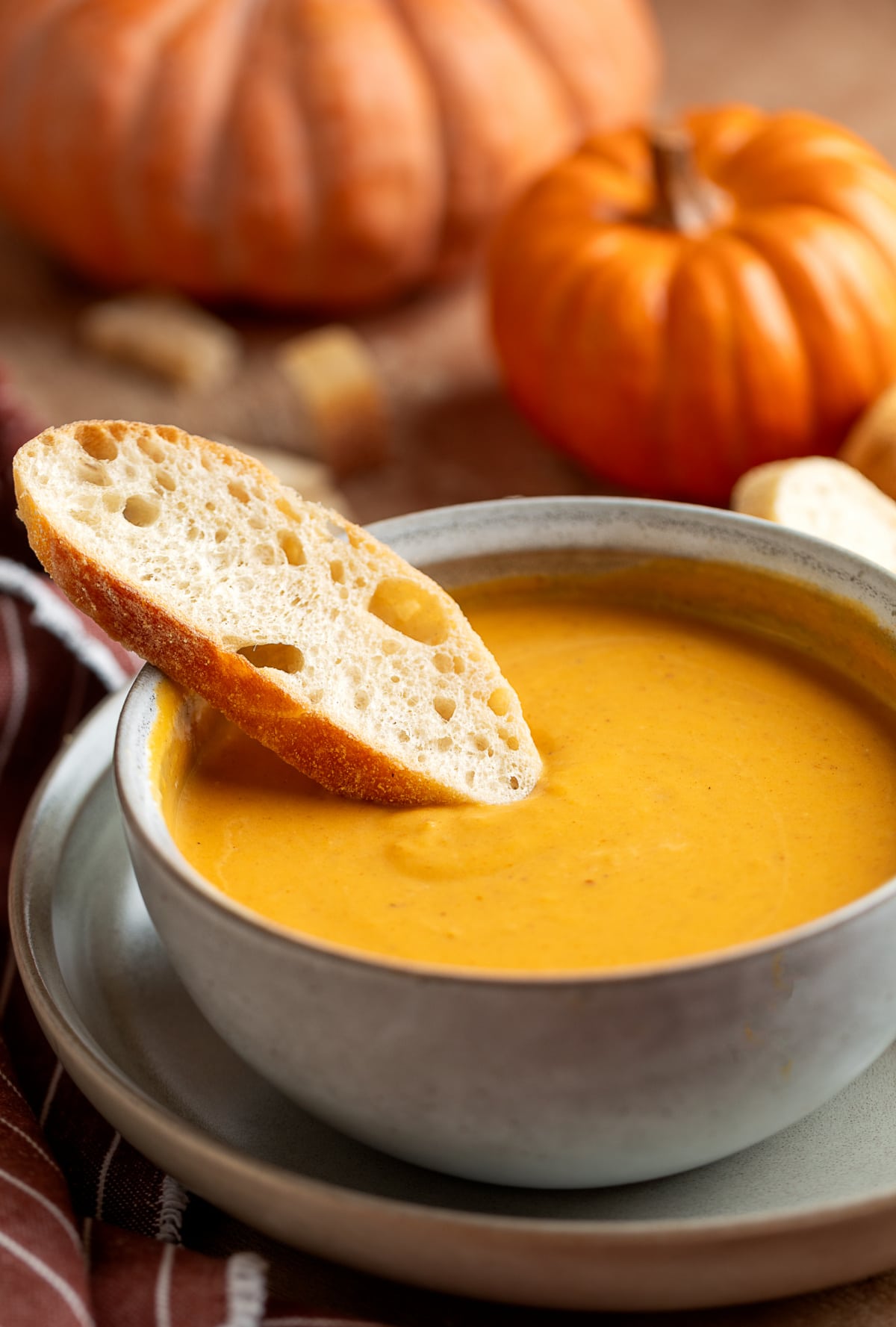 pumpkin soup with bread pumpkin soup with roasted garlic served in a bowl with a slice of crusty bread on the rim