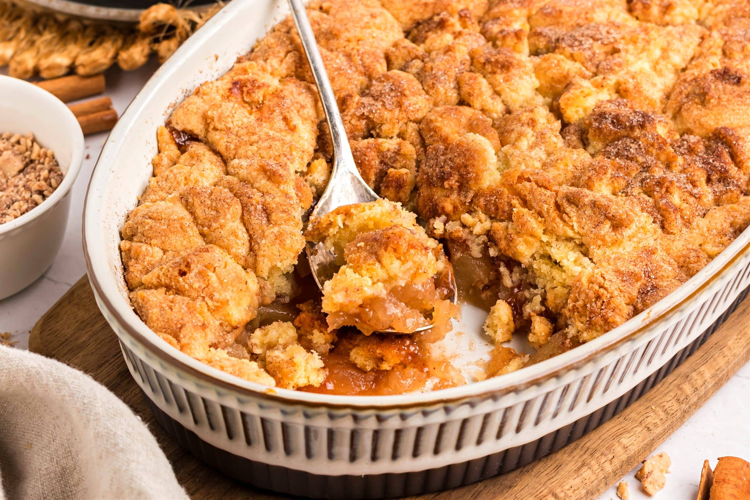 Apple cobbler with snickerdoodle cookie topping in oval baking dish.