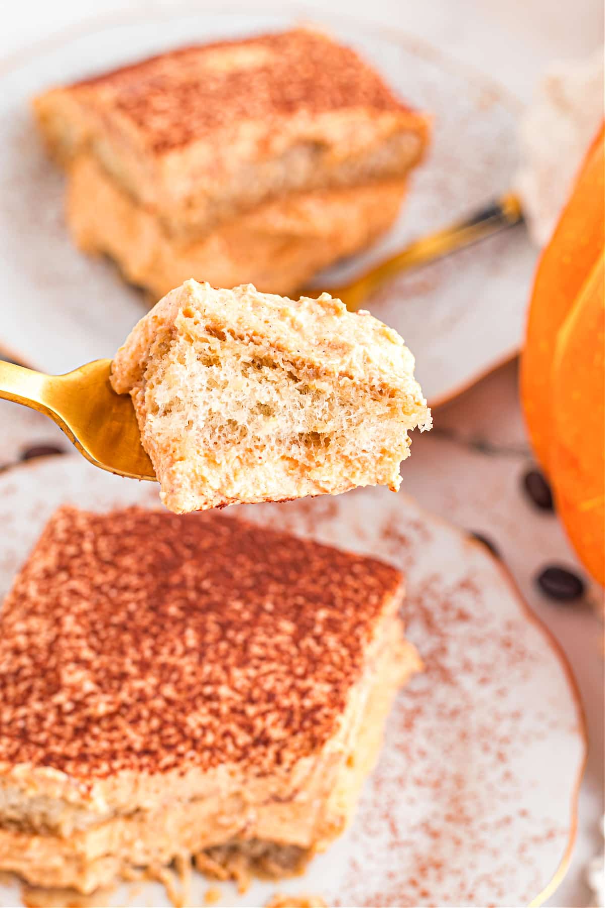 pumpkin tiramisu bite on fork Fork holding bite of pumpkin tiramisu with mascarpone cream and soaked ladyfinger