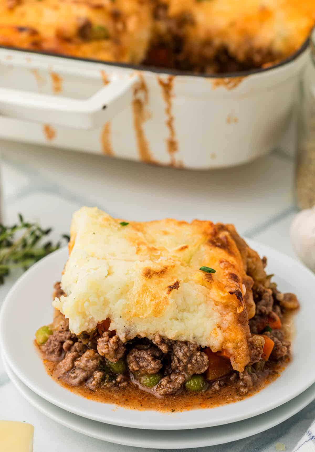 cottage pie serving on plate with beef and potato layers Slice of beef and vegetable pie with mashed potato topping served on a white plate, showing the rich filling and cheesy golden top.