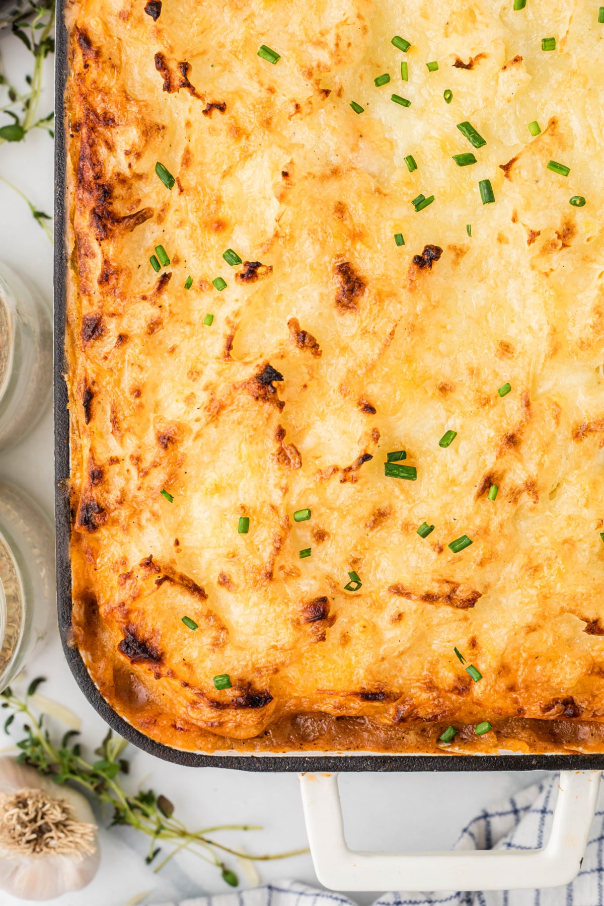 browned cheesy potato topping with chives Close-up of a bubbling potato and cheese bake with crisp, browned edges and a sprinkle of chives.