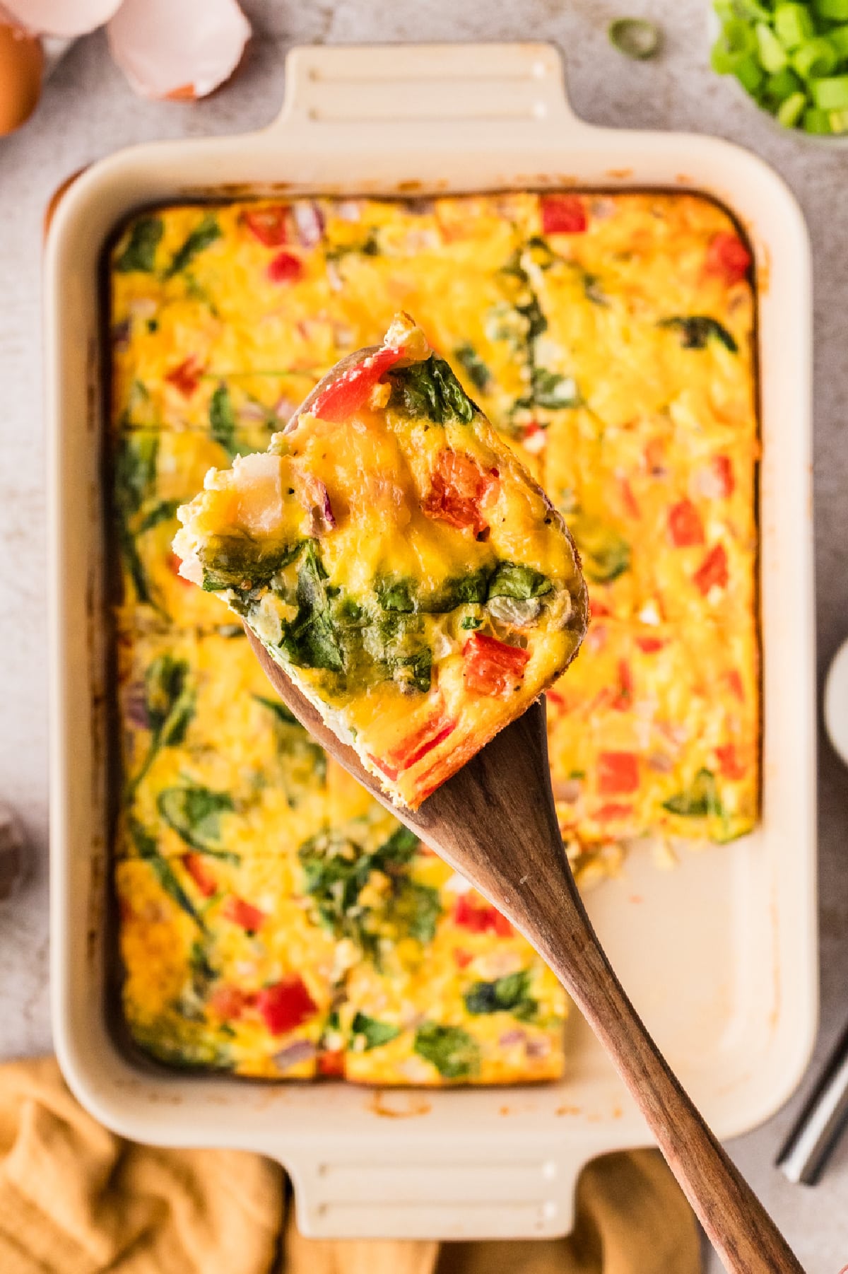 Slice of egg bake on spatula Egg bake with cottage cheese slice lifted from baking dish showing spinach and red pepper