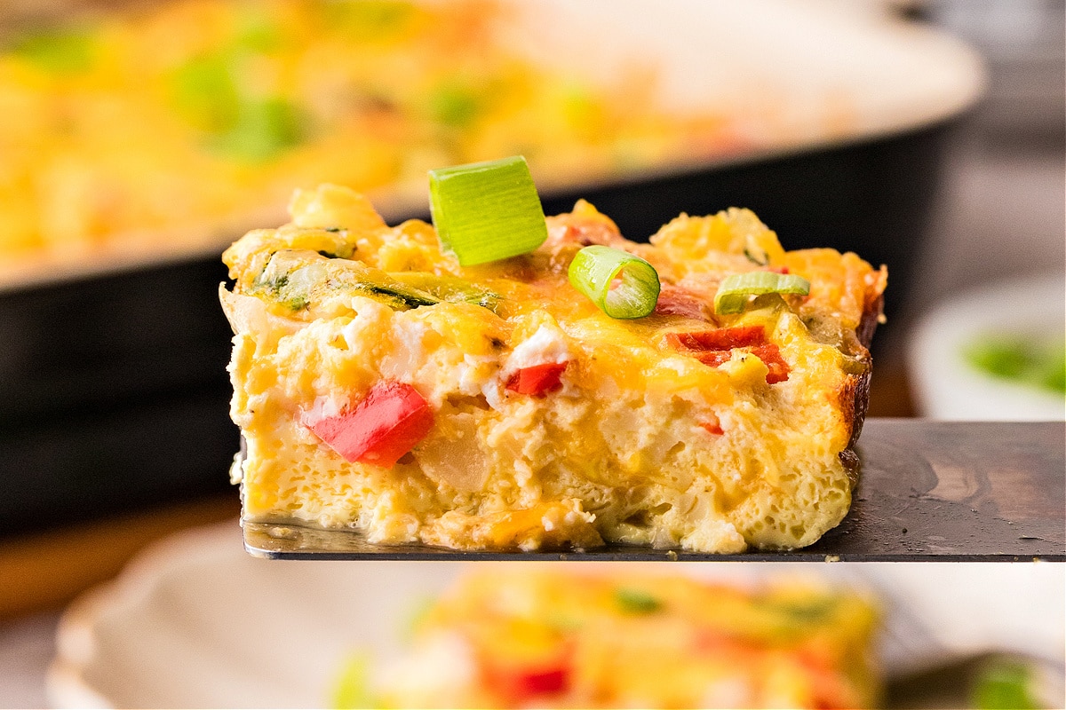 Serving of egg casserole with green onions Cottage cheese egg casserole square topped with green onions on spatula