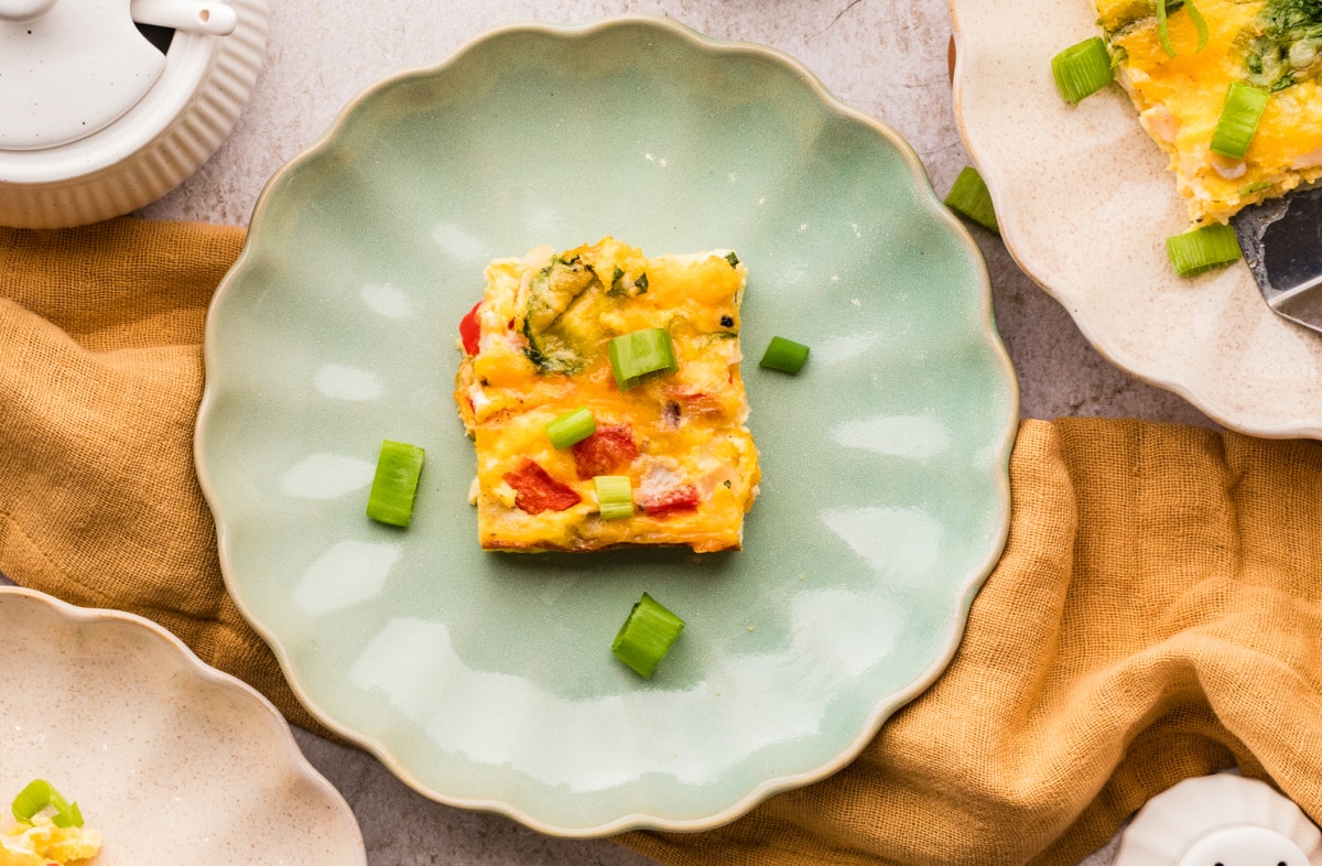 Serving of casserole on plate Cottage cheese breakfast casserole square on a green plate with green onion garnish