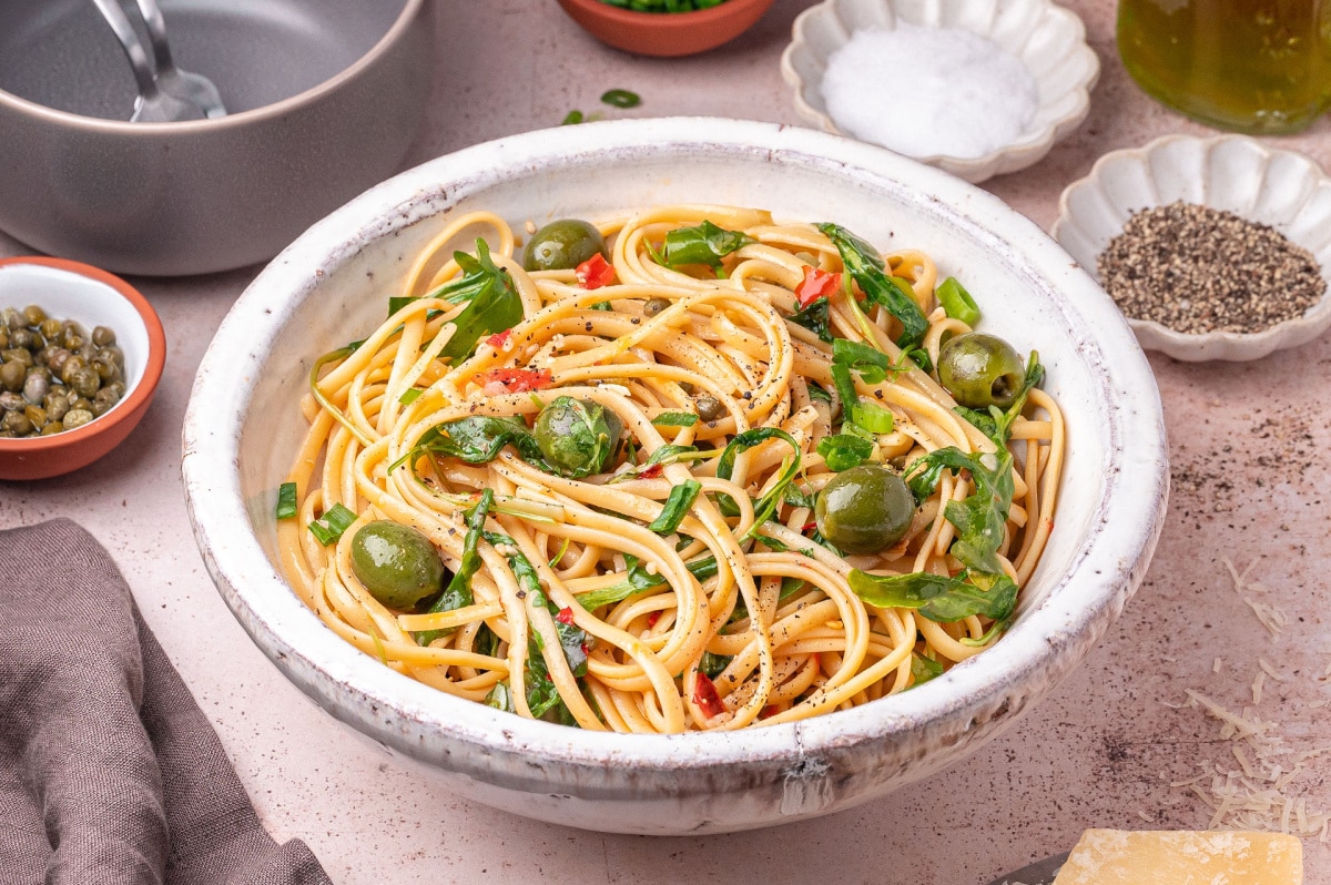 green-olive-puttanesca-pasta-finished-in-bowl Bowl of green olive puttanesca pasta with linguine, arugula, Castelvetrano olives, and Calabrian chilies.