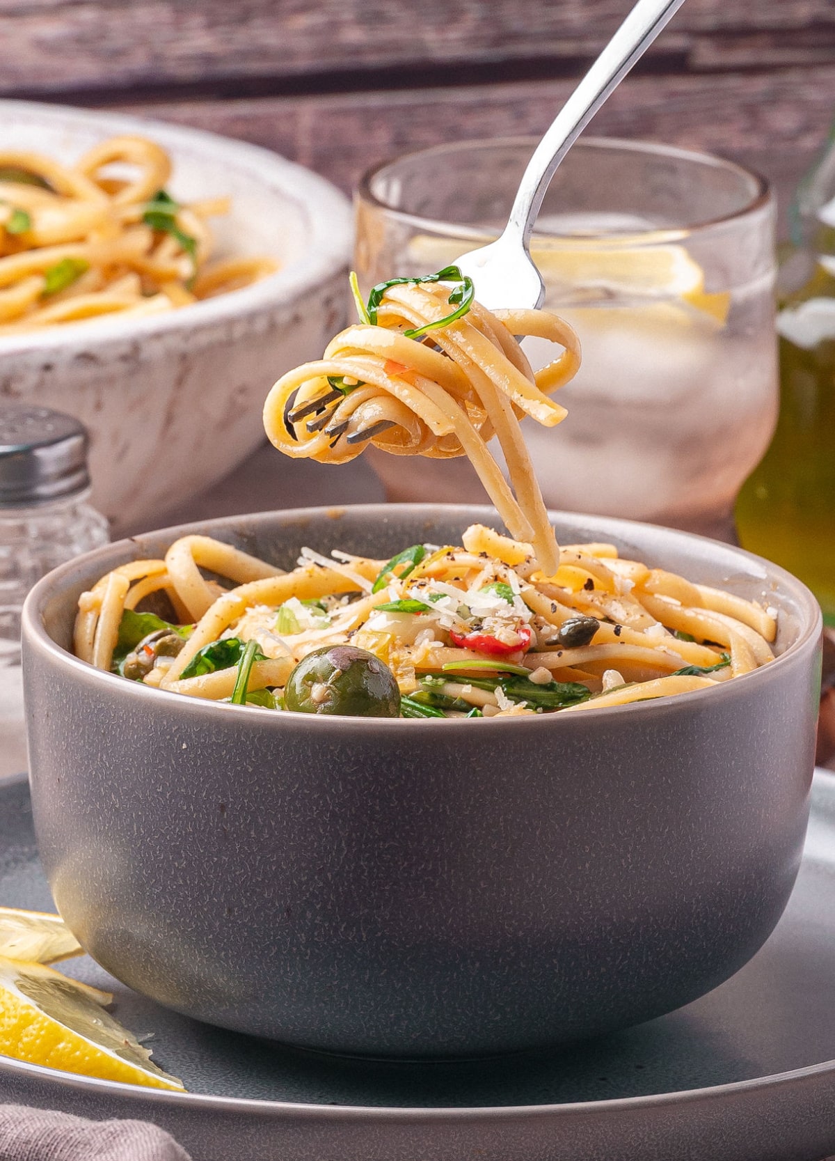 green-olive-pasta-recipe-fork-twirl Fork twirling a bite of green olive pasta recipe with arugula, Parmesan, and Calabrian chilies.