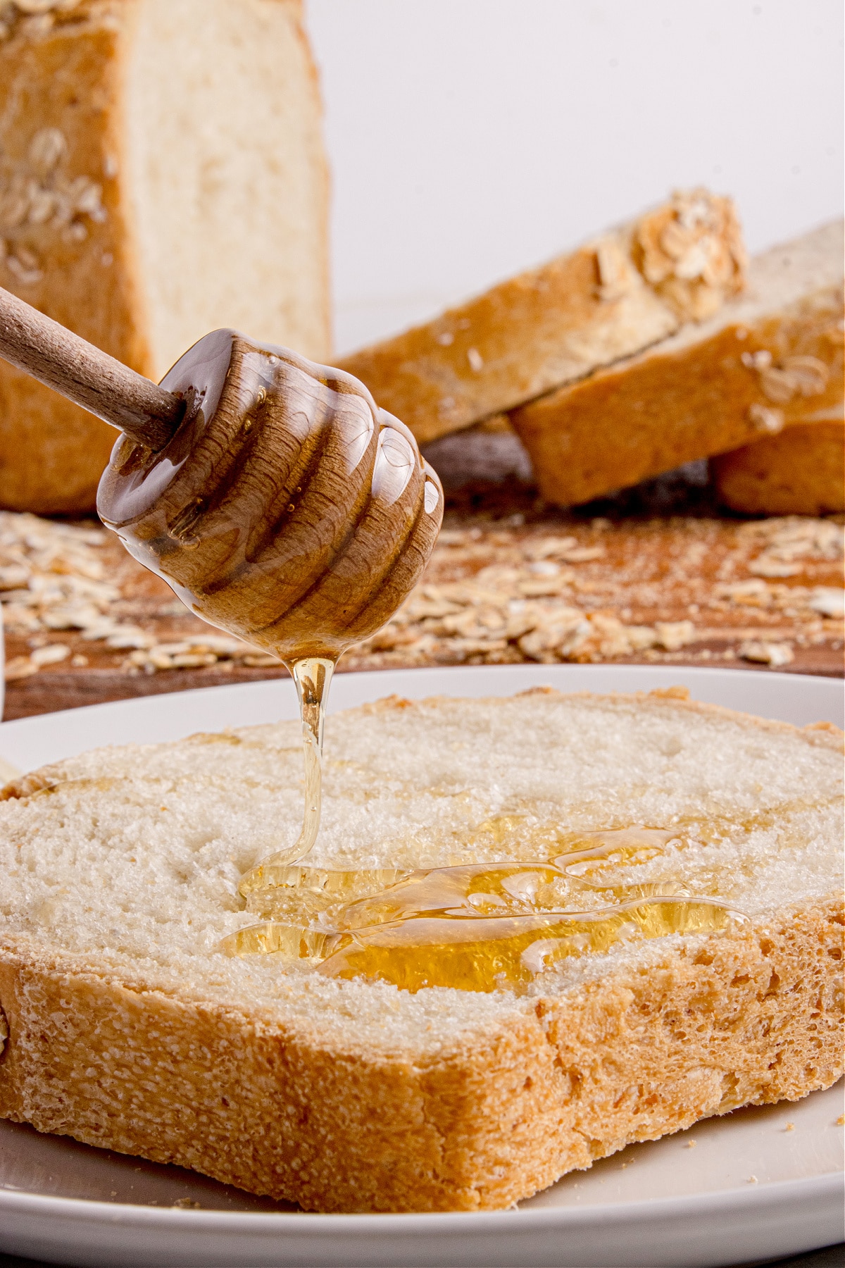oatmeal bread with honey drizzle Honey dripping onto a slice of soft oatmeal bread.
