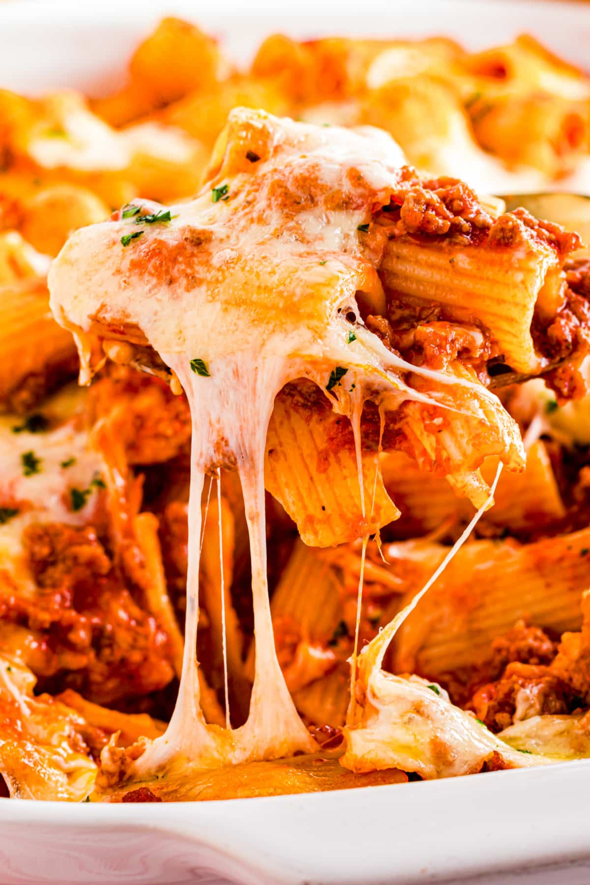 Baked rigatoni with beef, mozzarella, and red sauce bubbling in the pan with melted cheese pull by Noble Pig