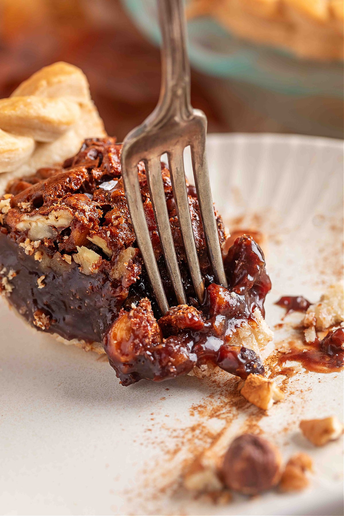 A fork breaking into a gooey slice of chocolate hazelnut pecan pie, revealing the Nutella-rich filling and toasted nuts.