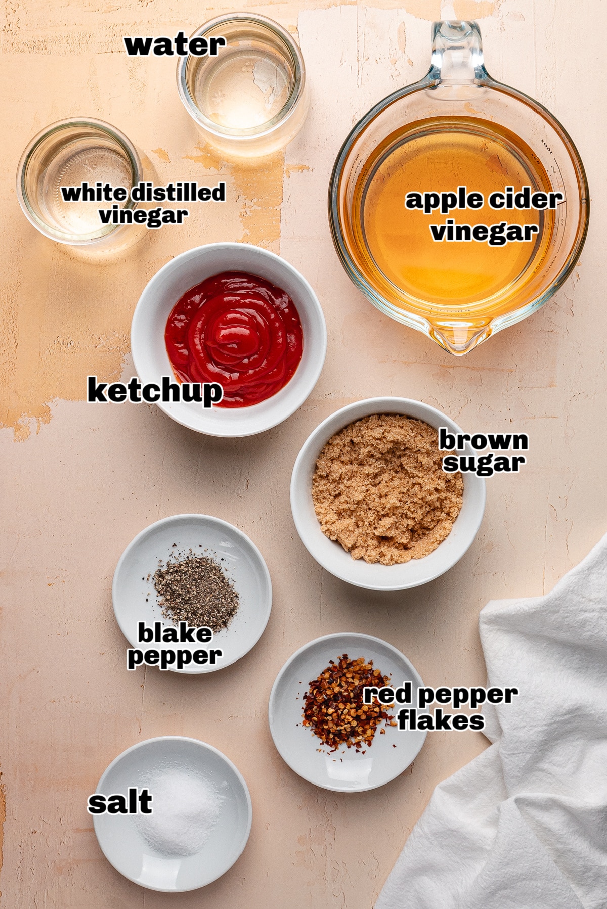 Western Carolina BBQ sauce ingredients on countertop. Ingredients for Western Carolina BBQ sauce including apple cider vinegar, ketchup, brown sugar, red pepper flakes, salt, pepper, and water.