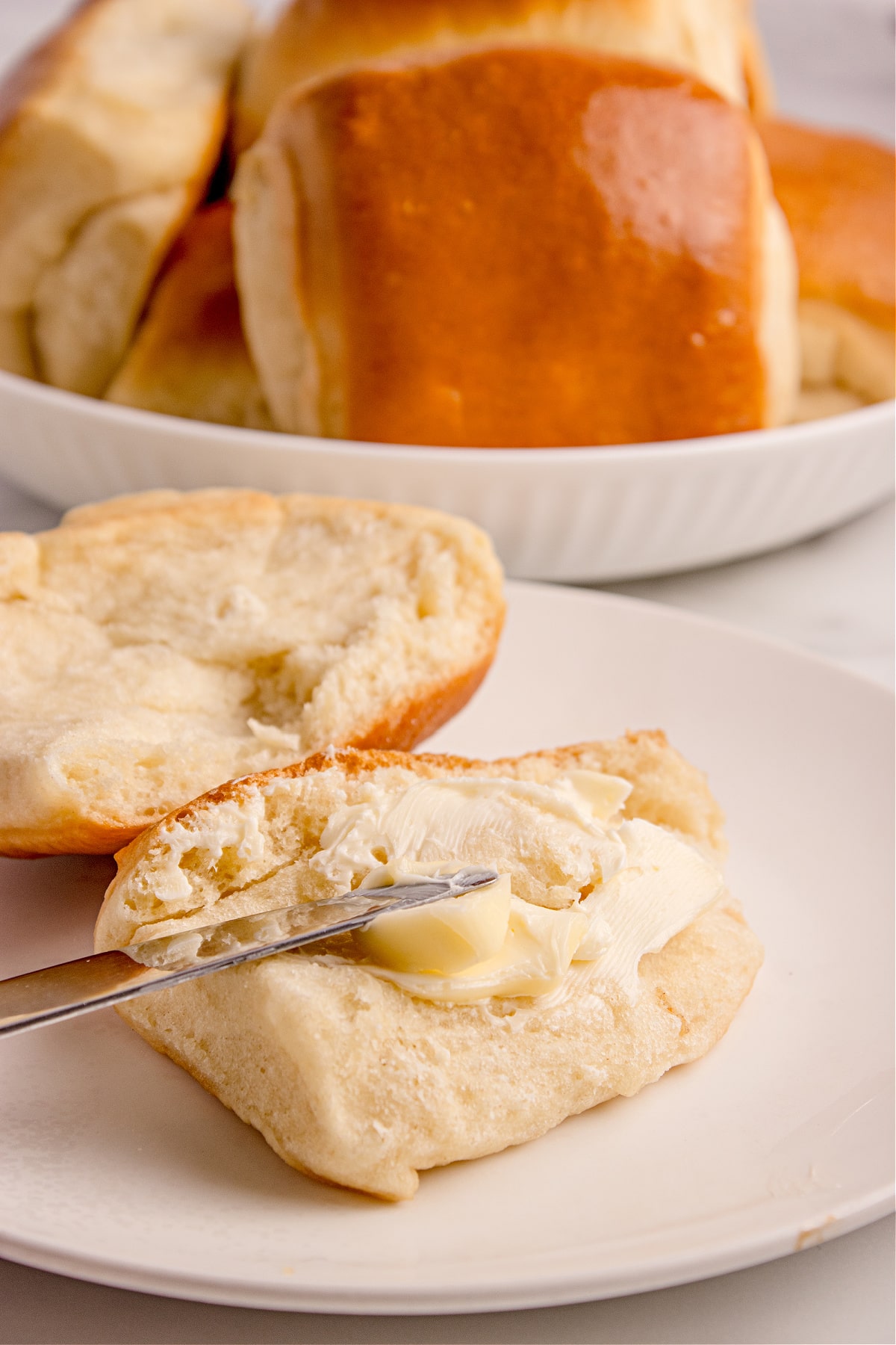 Buttered Parker House Roll split open to show the fluffy interior typical of soft dinner rolls.