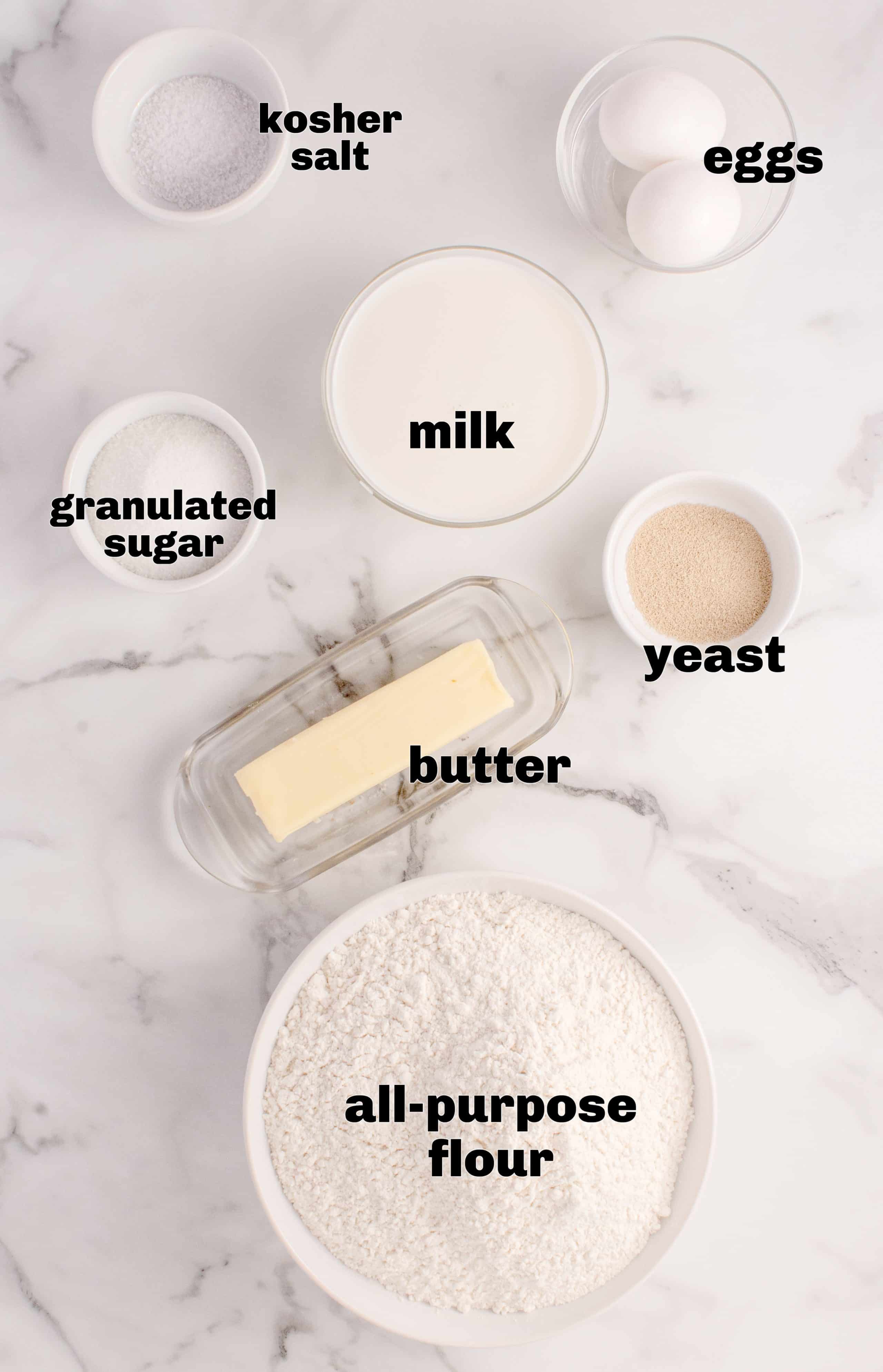 Ingredients for classic Parker House Rolls including flour, yeast, warm milk, butter, sugar, and eggs.