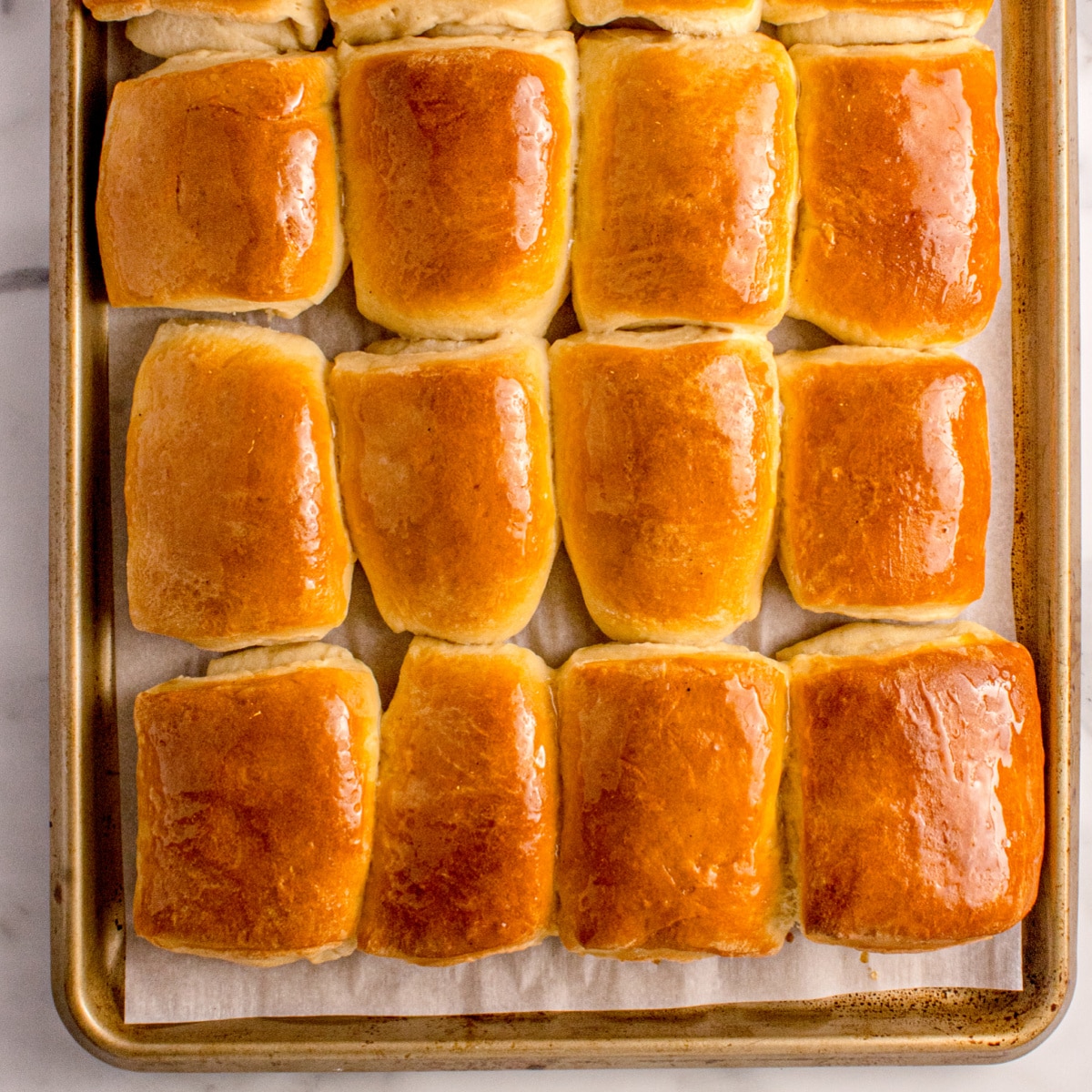 Fluffy Parker House Rolls made from enriched dough and brushed with melted butter for a shiny finish.
