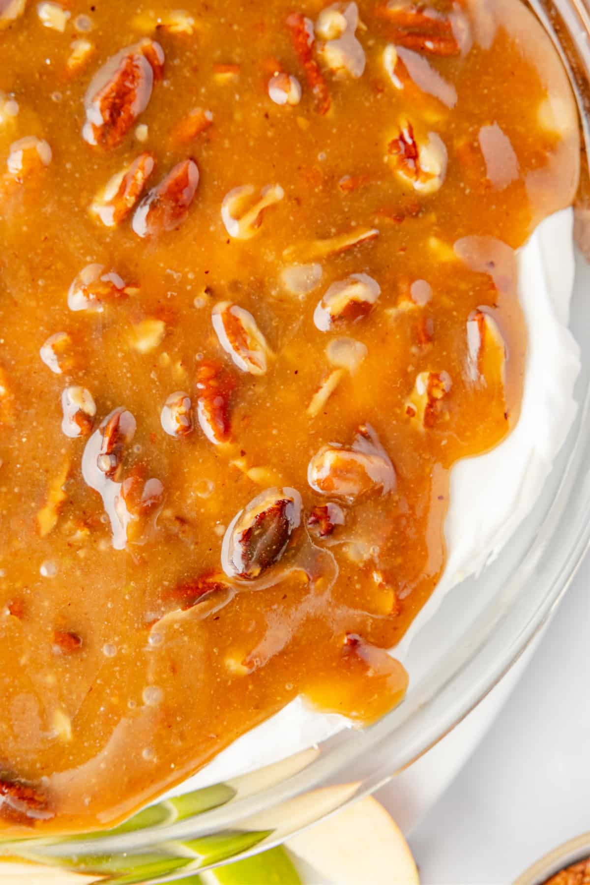 Caramel pecan topping layered over a cream cheese dessert dip Close-up of pecan pie dip showing the warm caramel pecan topping over the cold cream cheese layer, highlighting the glossy brown sugar texture.