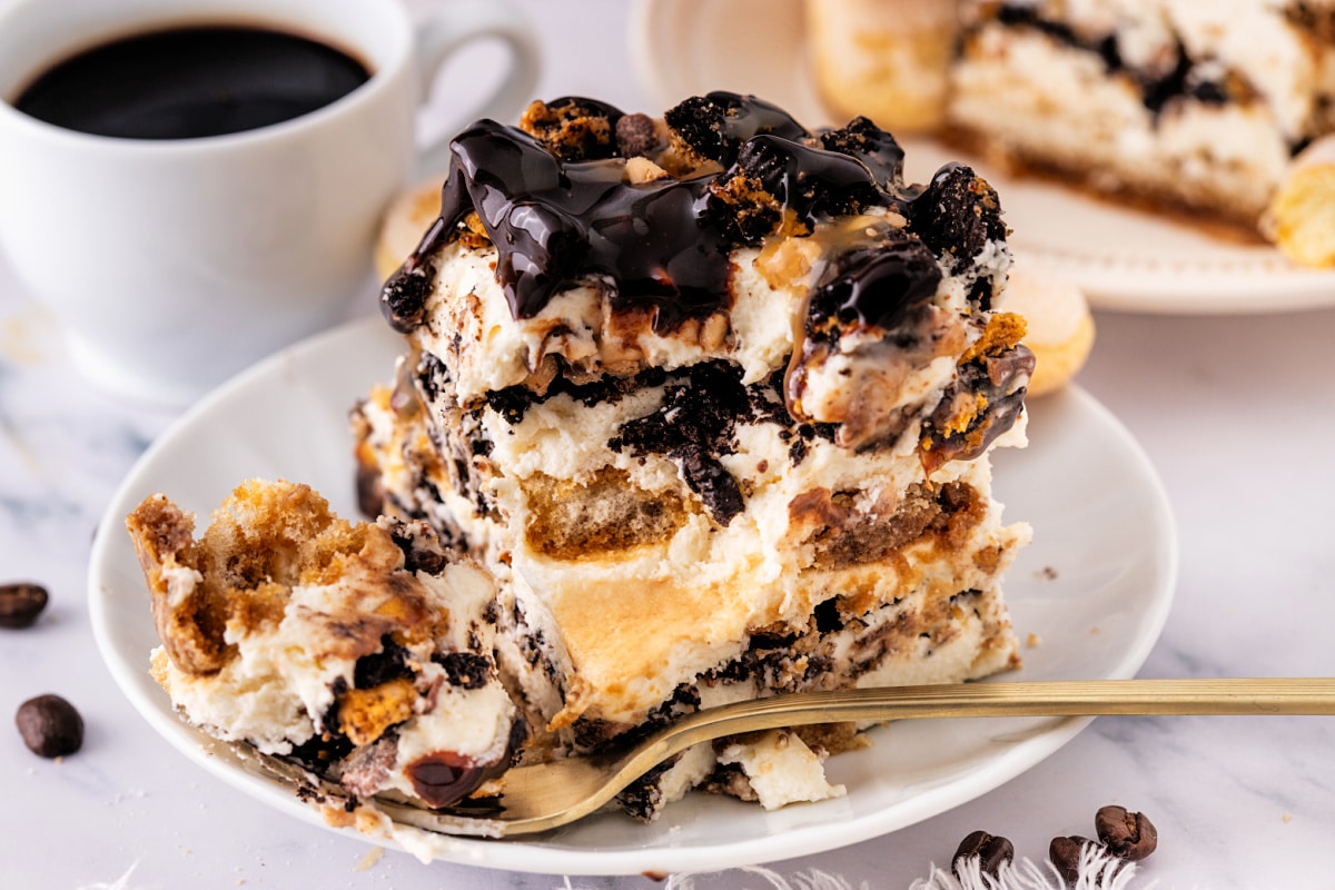 Slice of toffee tiramisu by Noble Pig with espresso-soaked ladyfingers, mascarpone toffee cream, chocolate drizzle, and crushed Toffee Crunch OREOs.