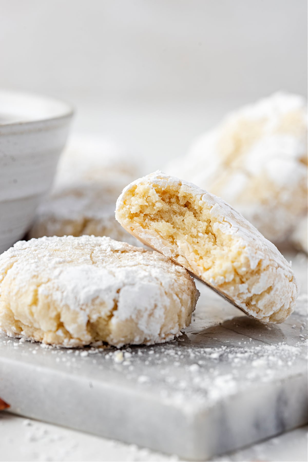 A close-up stack of snowy, crackled Amaretti cookies showing their soft, tender centers.