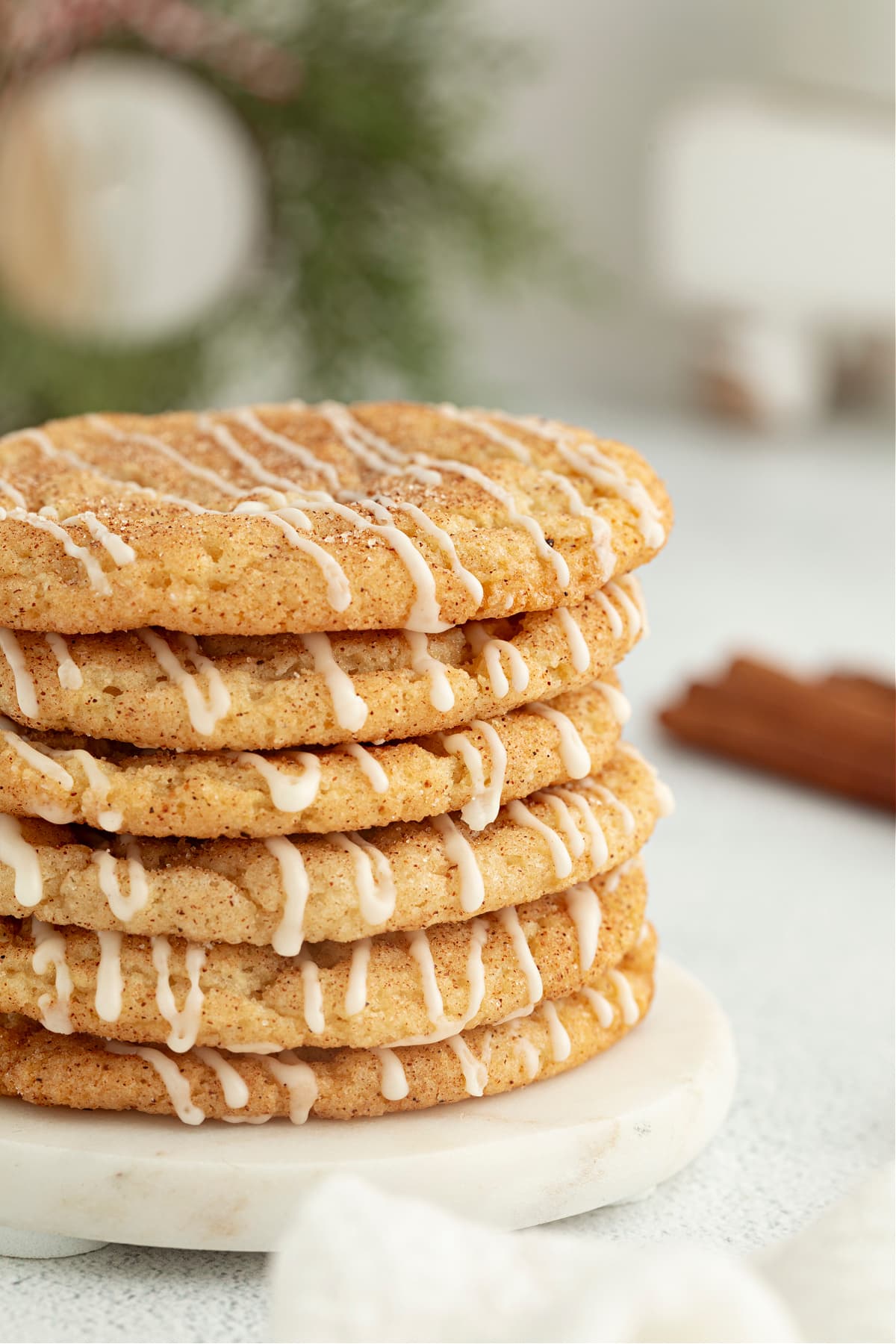 Eggnog snickerdoodles stacked beside a glass of eggnog for a cozy holiday cookie presentation.