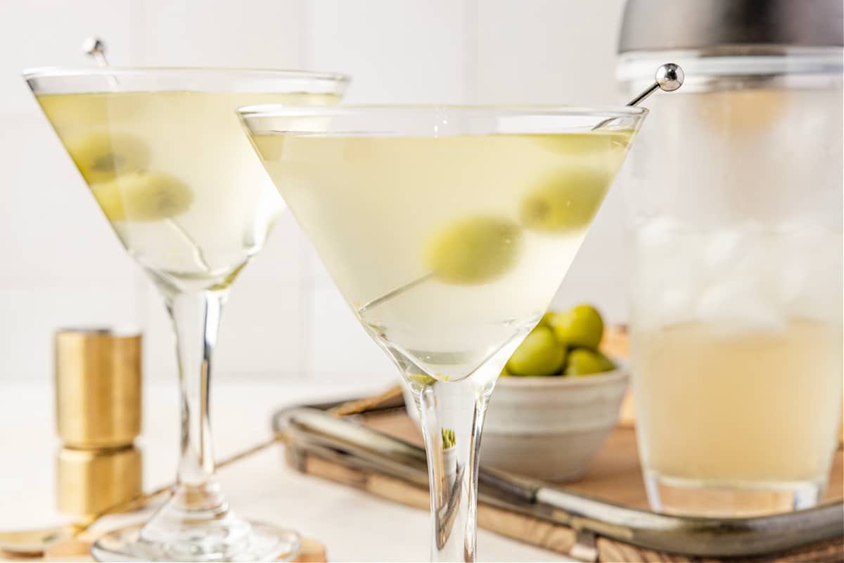 A very dirty martini resting in a chilled glass with green olives suspended in the pale, briny cocktail.