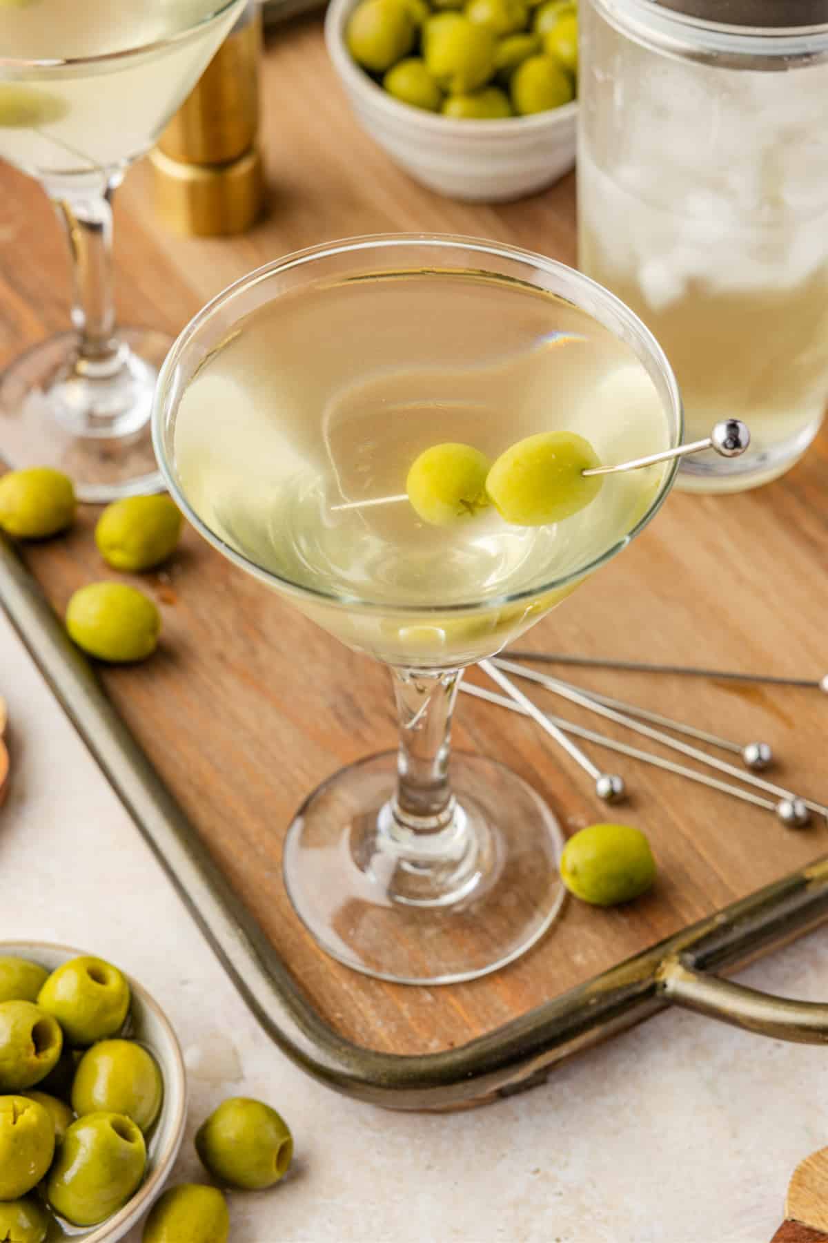 Top-down view of a briny extra dirty martini with two green olives skewered across the chilled glass.