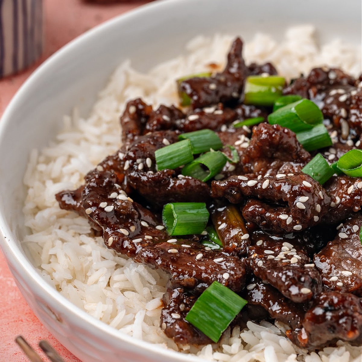 Ginger beef served over white rice with sesame seeds and green onions.