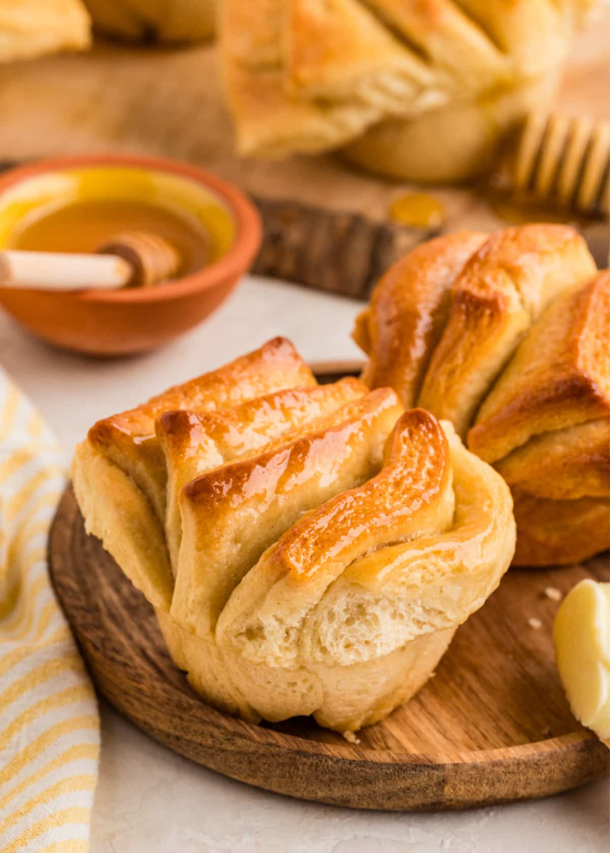 A close view of honey butter pull-apart rolls showing fluffy layers, a tender crumb, and a lightly glazed golden surface. Honey butter pull-apart rolls baked in a muffin tin with soft layered sides and a golden top.