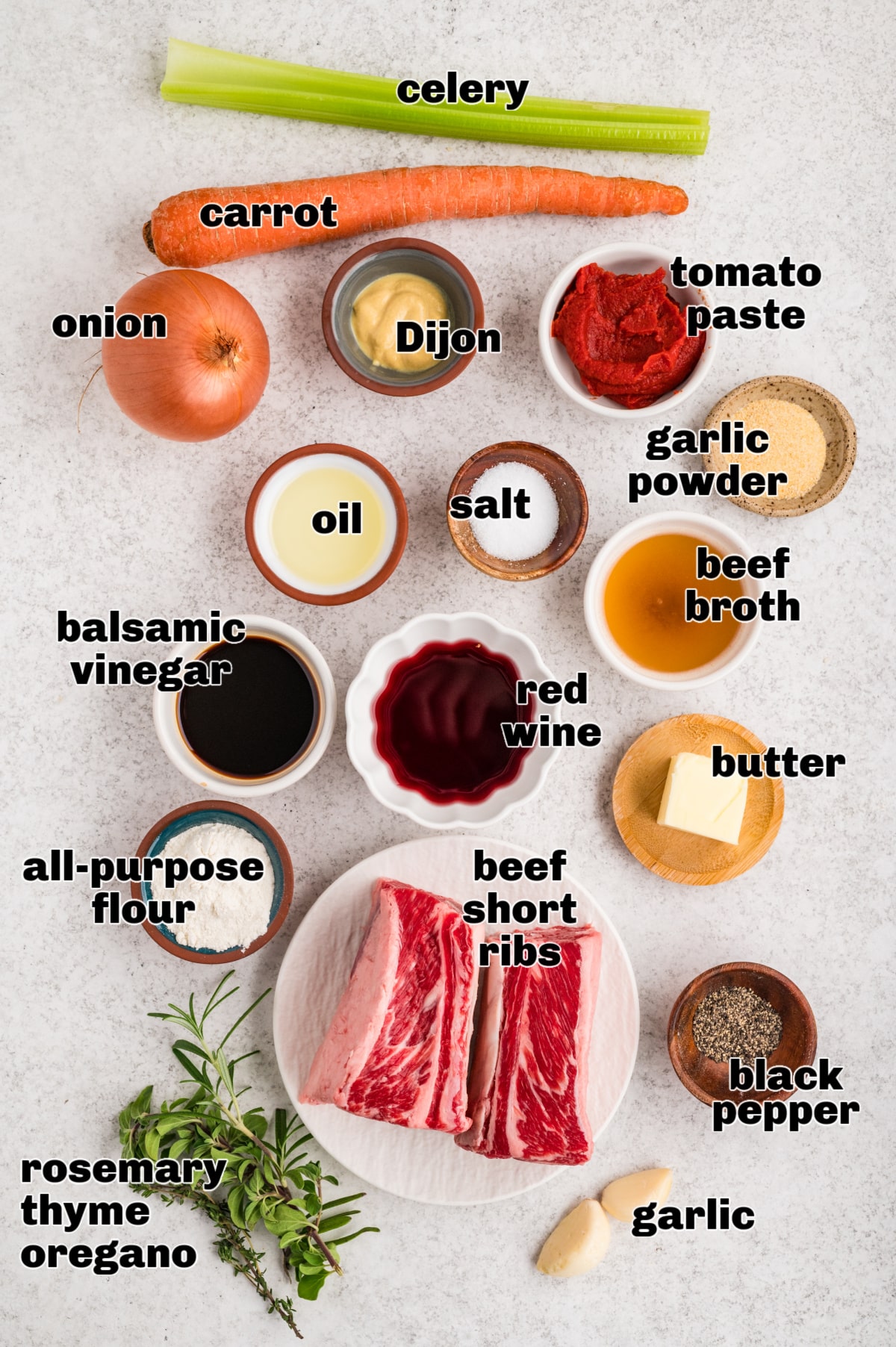 Ingredients arranged for making braised beef short ribs with aromatics, herbs, broth, and sauce components. Ingredients laid out for oven-braised beef short ribs, including bone-in short ribs, vegetables, herbs, broth, wine, and seasonings.