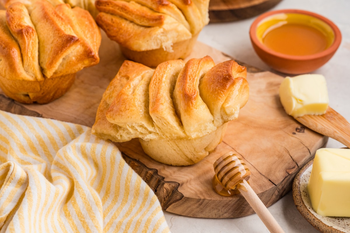 A close look at the layered structure of the rolls, showing their airy crumb and buttery folds after baking. Soft pull-apart rolls with visible layers and a fluffy interior resting on a wooden board.
