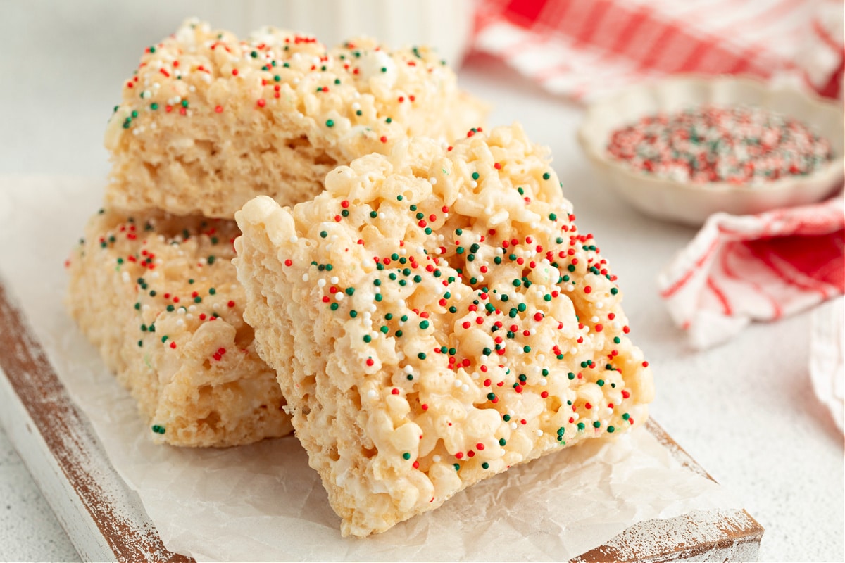 Stacked sugar cookie–flavored Rice Krispie treat squares covered in red, green, and white holiday sprinkles.
