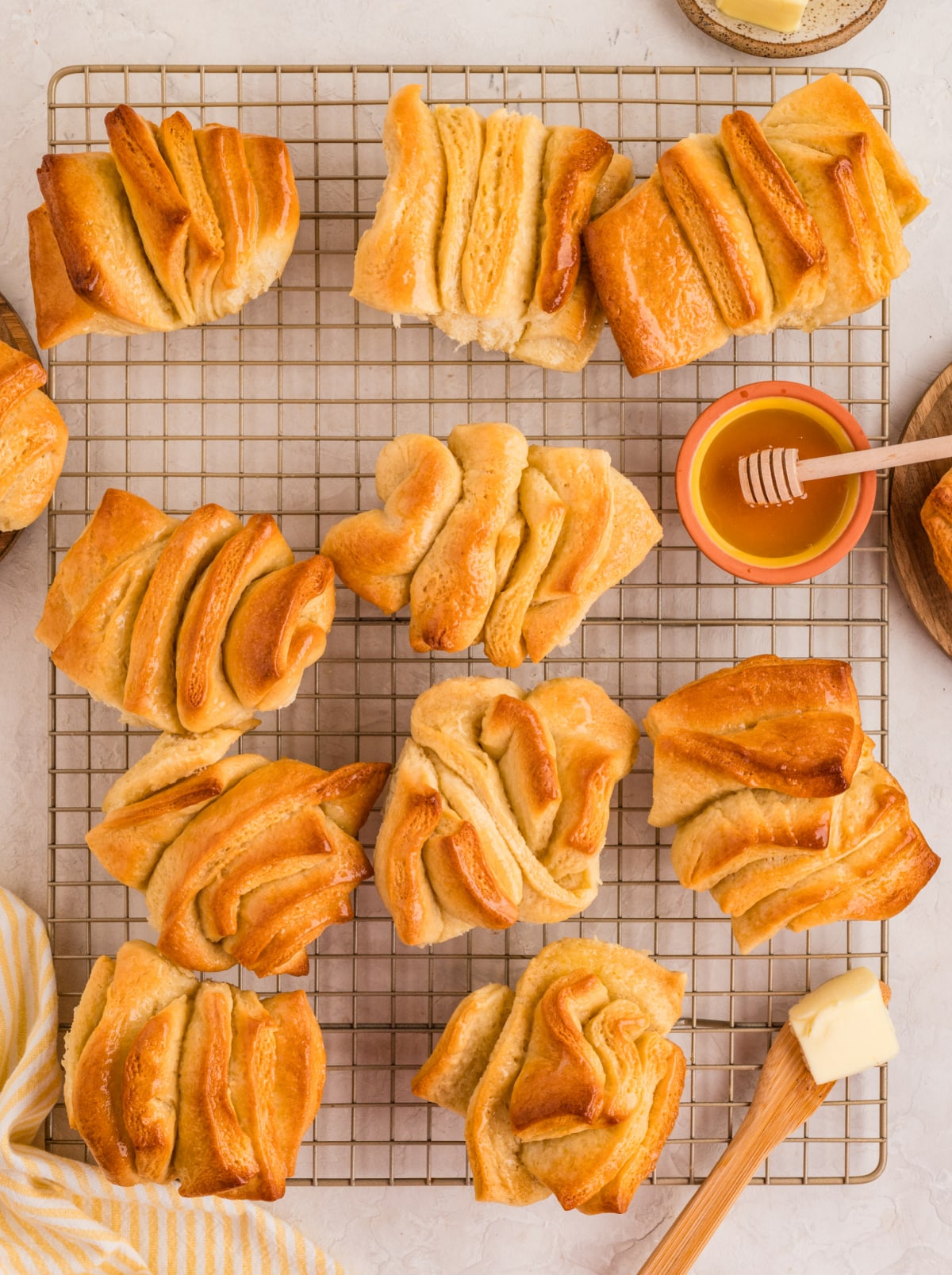 Freshly baked honey butter pull-apart rolls cooling on a rack, showing crisp golden edges and soft folded layers. Soft honey butter pull-apart rolls cooling on a wire rack with a golden layered finish.