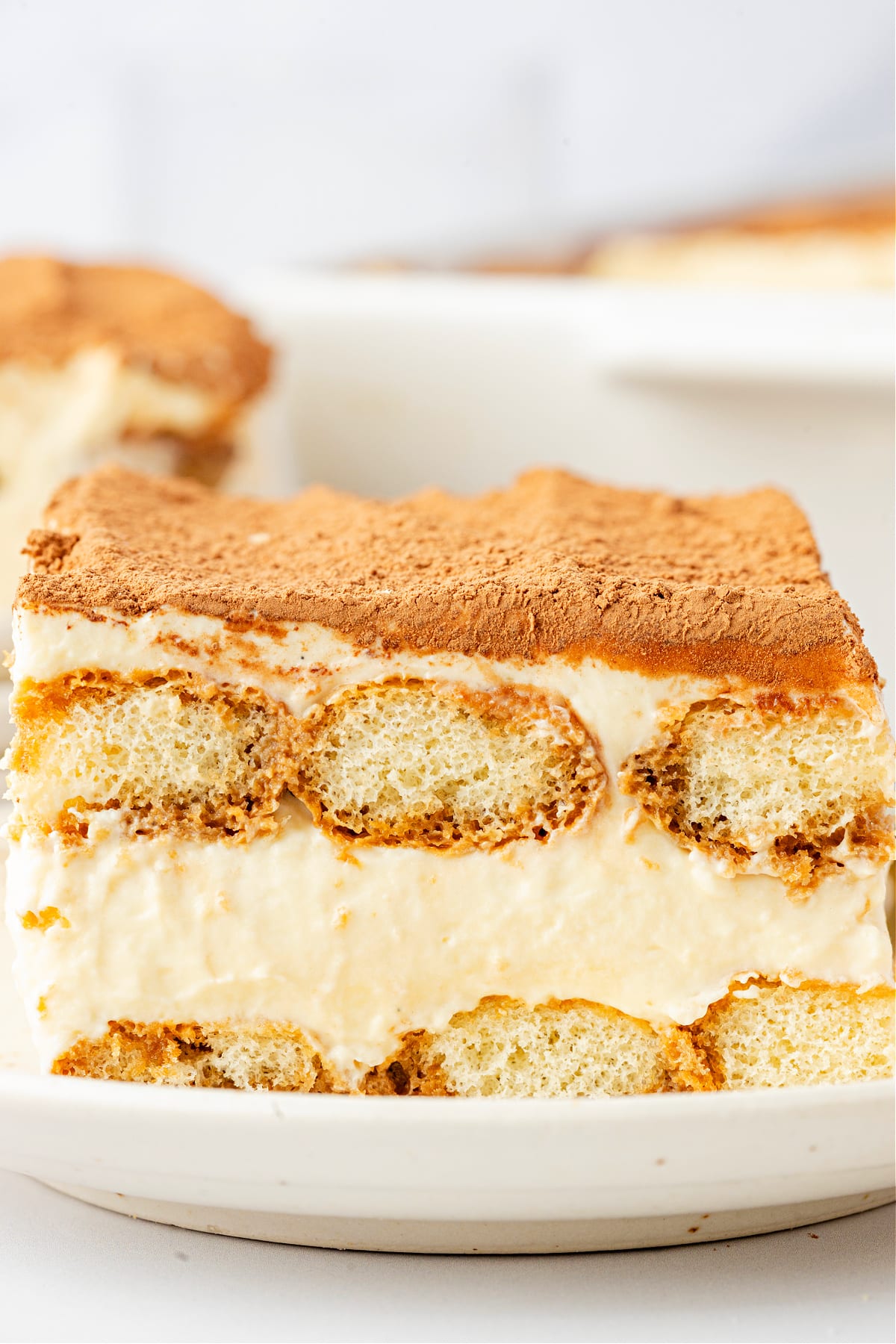 A close-up slice of Baileys Irish Cream Tiramisu showing distinct layers of mascarpone cream and espresso-soaked ladyfingers. Baileys Irish Cream Tiramisu with visible layers of espresso-soaked ladyfingers and mascarpone cream, finished with a cocoa-dusted top.