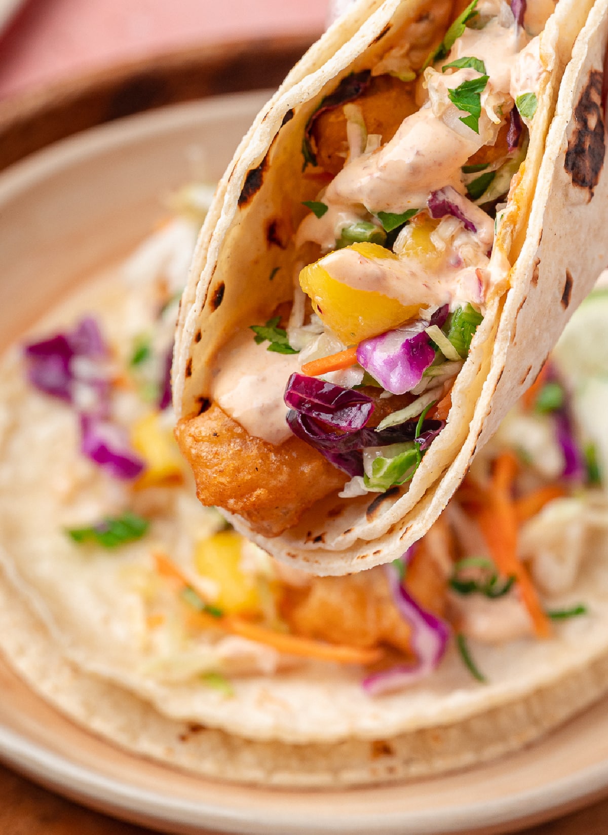 Beer-battered fish tacos with mango slaw and chipotle lime sauce folded into warm corn tortillas.