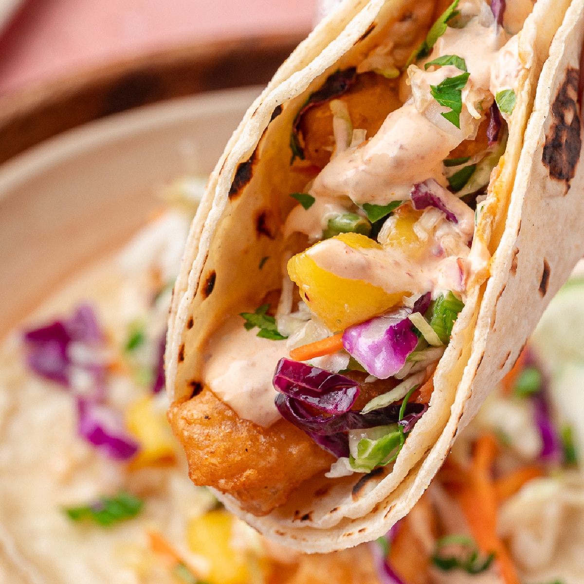 Beer-battered fish tacos with mango slaw served on warm corn tortillas with lime
