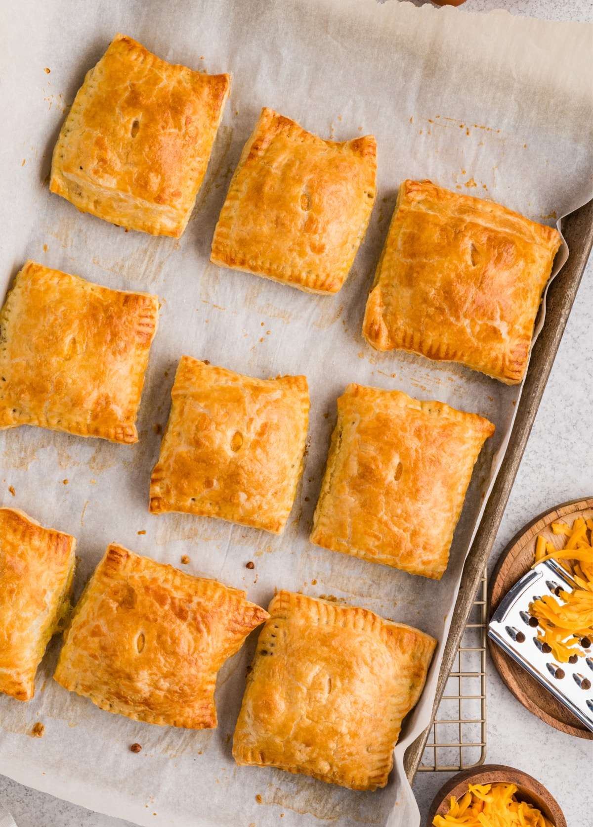 Flaky sausage, egg, and cheese breakfast pastries baked until golden and arranged on a parchment-lined baking sheet.