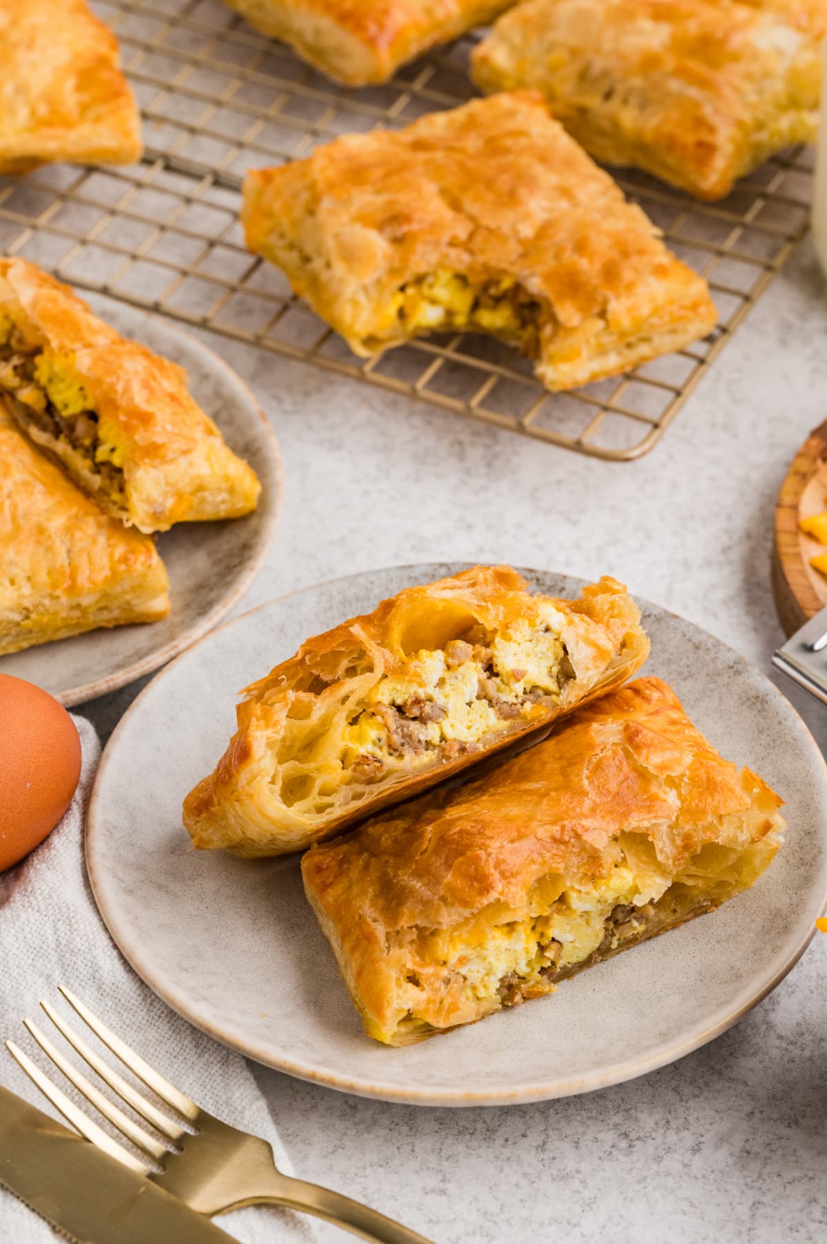 Flaky sausage, egg, and cheese breakfast pastries split open to show the golden puff pastry layers and savory filling inside.