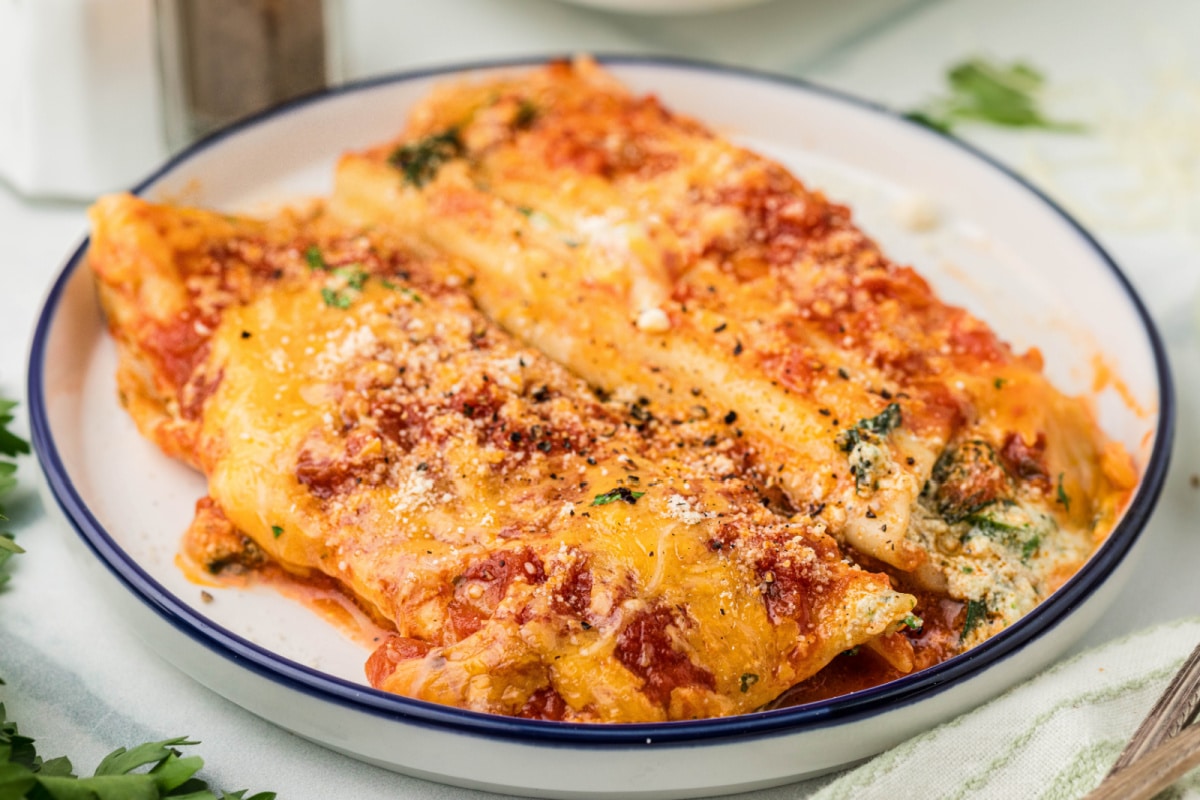 Plated baked manicotti with ricotta and spinach filling, marinara sauce, and melted sharp cheddar