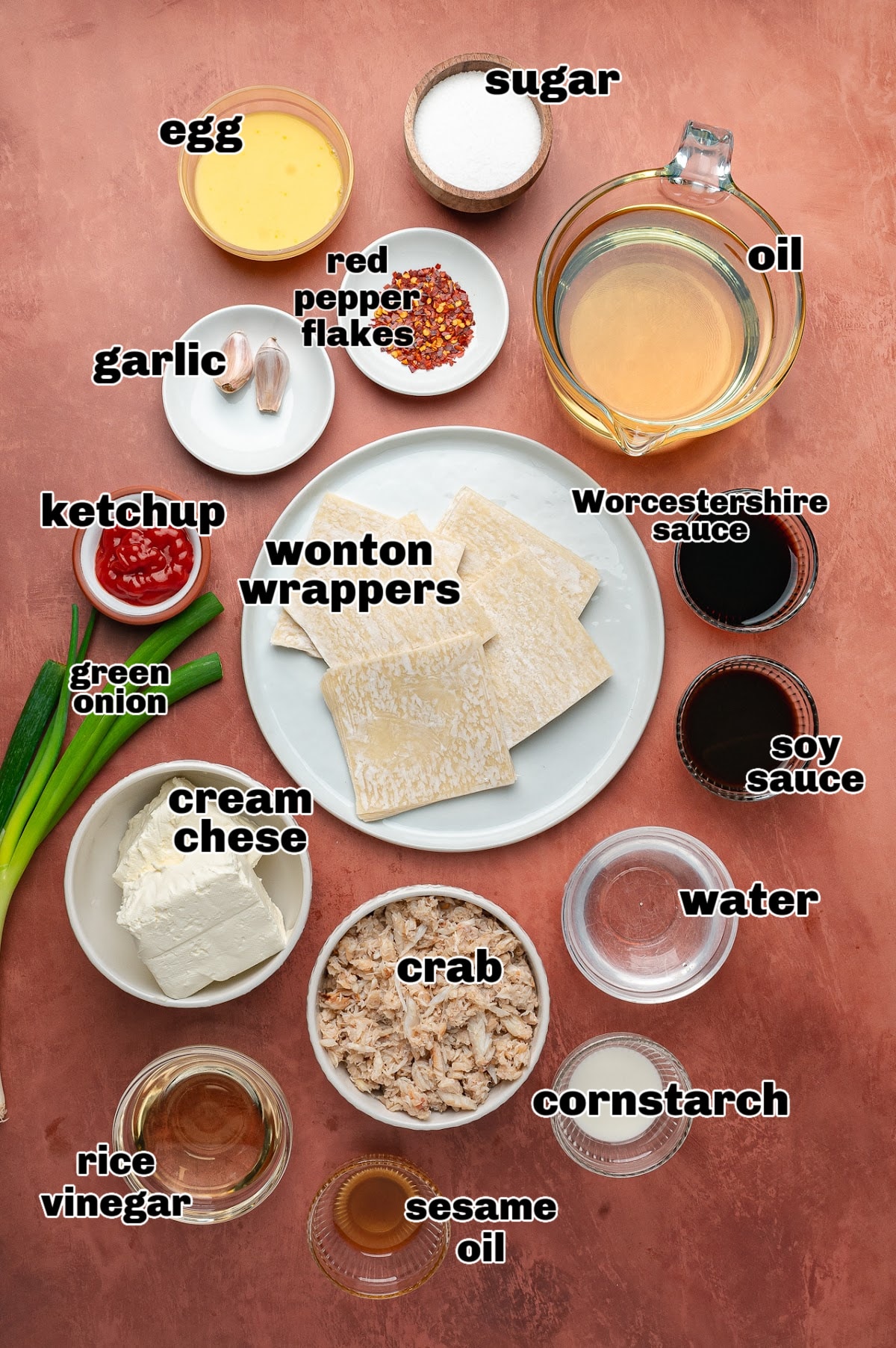 Ingredients for making crab rangoon and sweet and spicy dipping sauce, including cream cheese, crab, wonton wrappers, green onions, garlic, and sauce components.