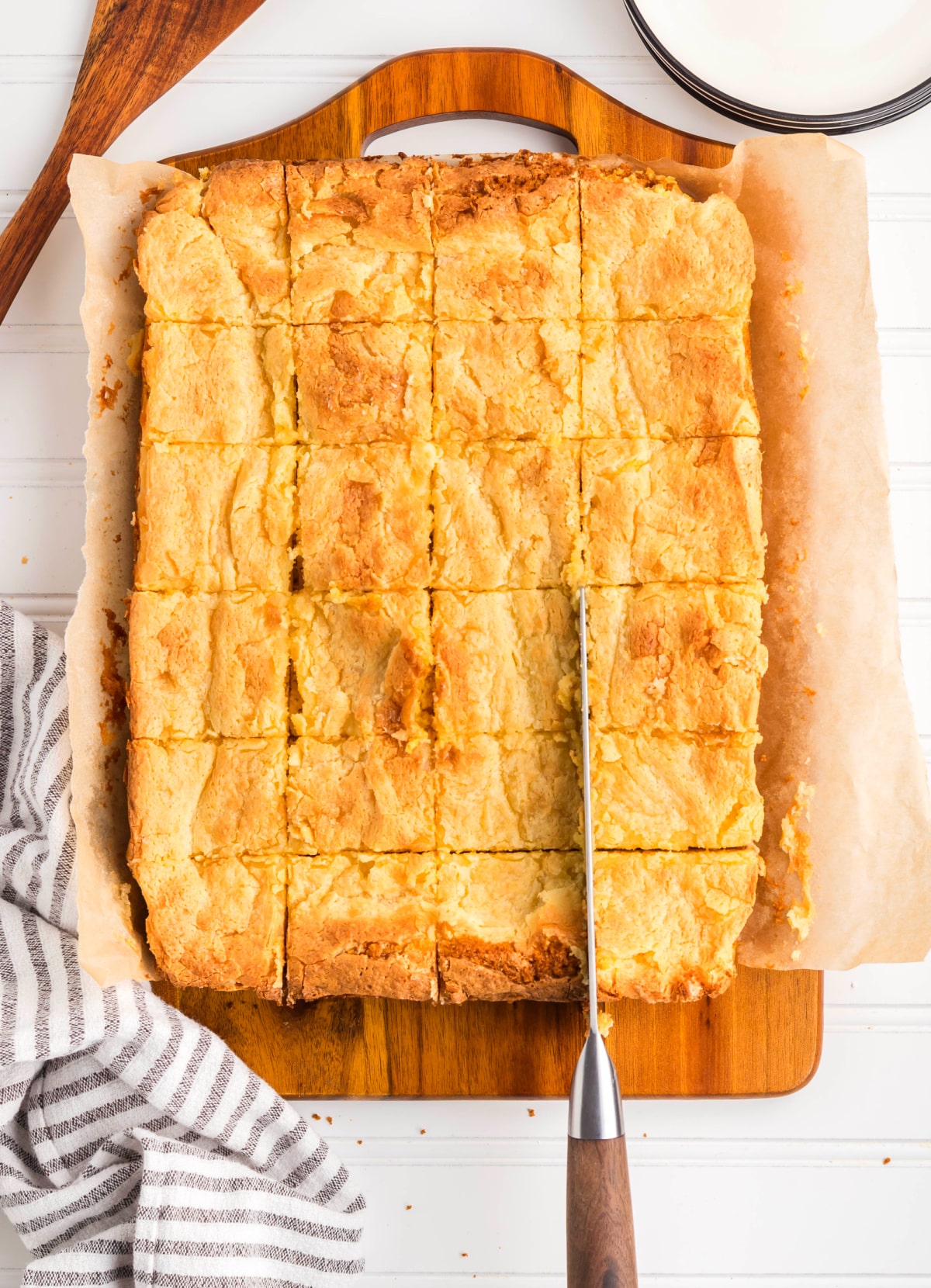 Gooey butter cake sliced into squares in the baking pan. Gooey butter cake cut into even squares while still in the pan, showing the soft interior and golden top.