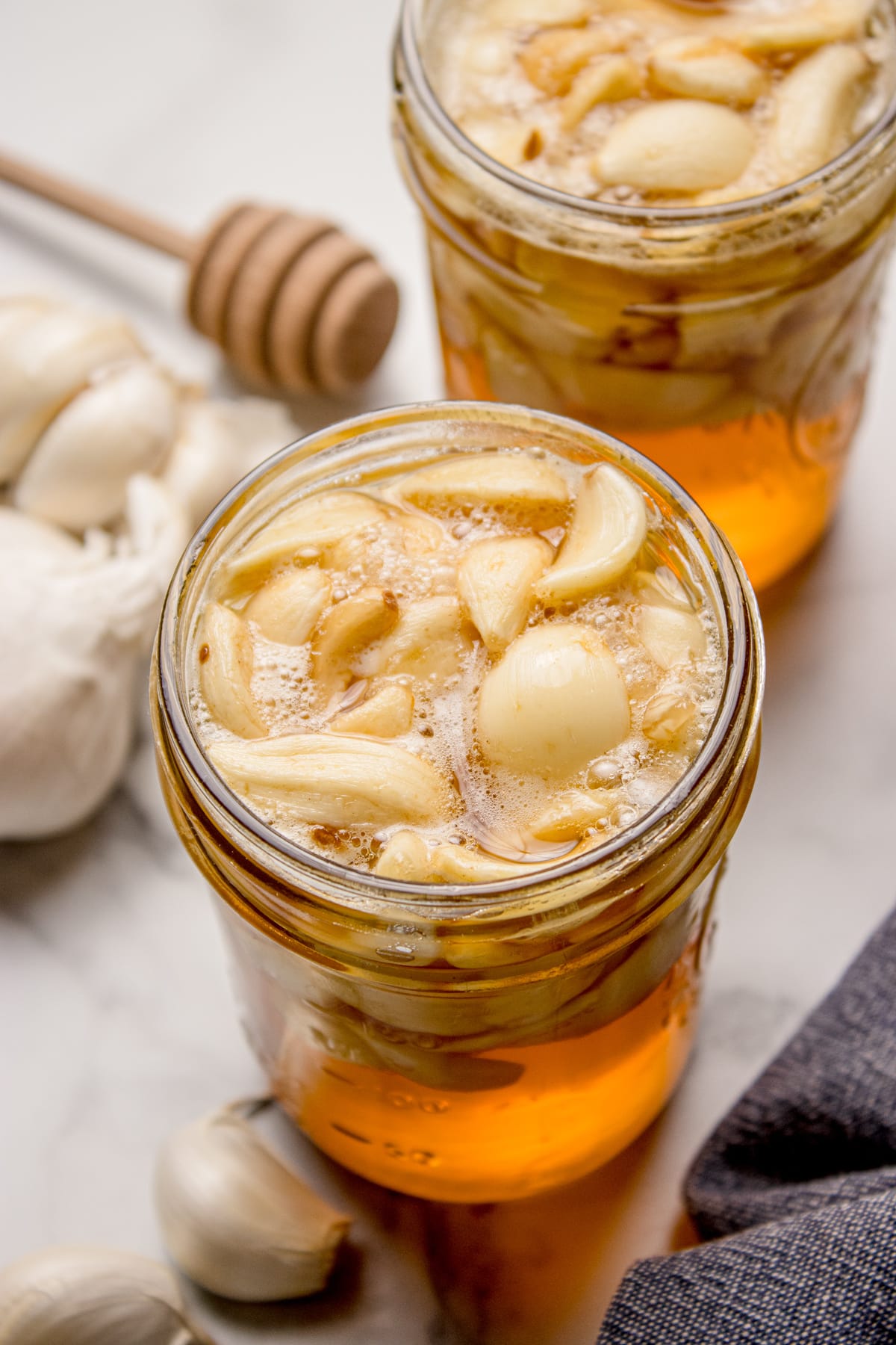 Fermented honey garlic bubbling at room temperature as the honey thins and the garlic releases gas. Fermented honey garlic actively bubbling in a mason jar, with whole garlic cloves floating as fermentation continues.