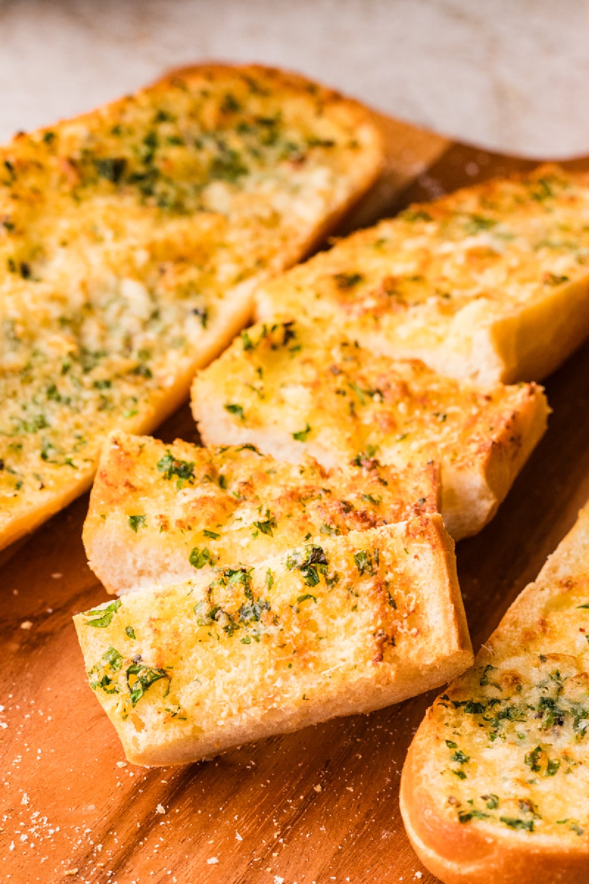 Slices of garlic confit air fryer bread crisped until golden on the edges and still soft in the middle Garlic confit air fryer bread with golden, crisp edges and a soft center, finished with parsley and Parmesan