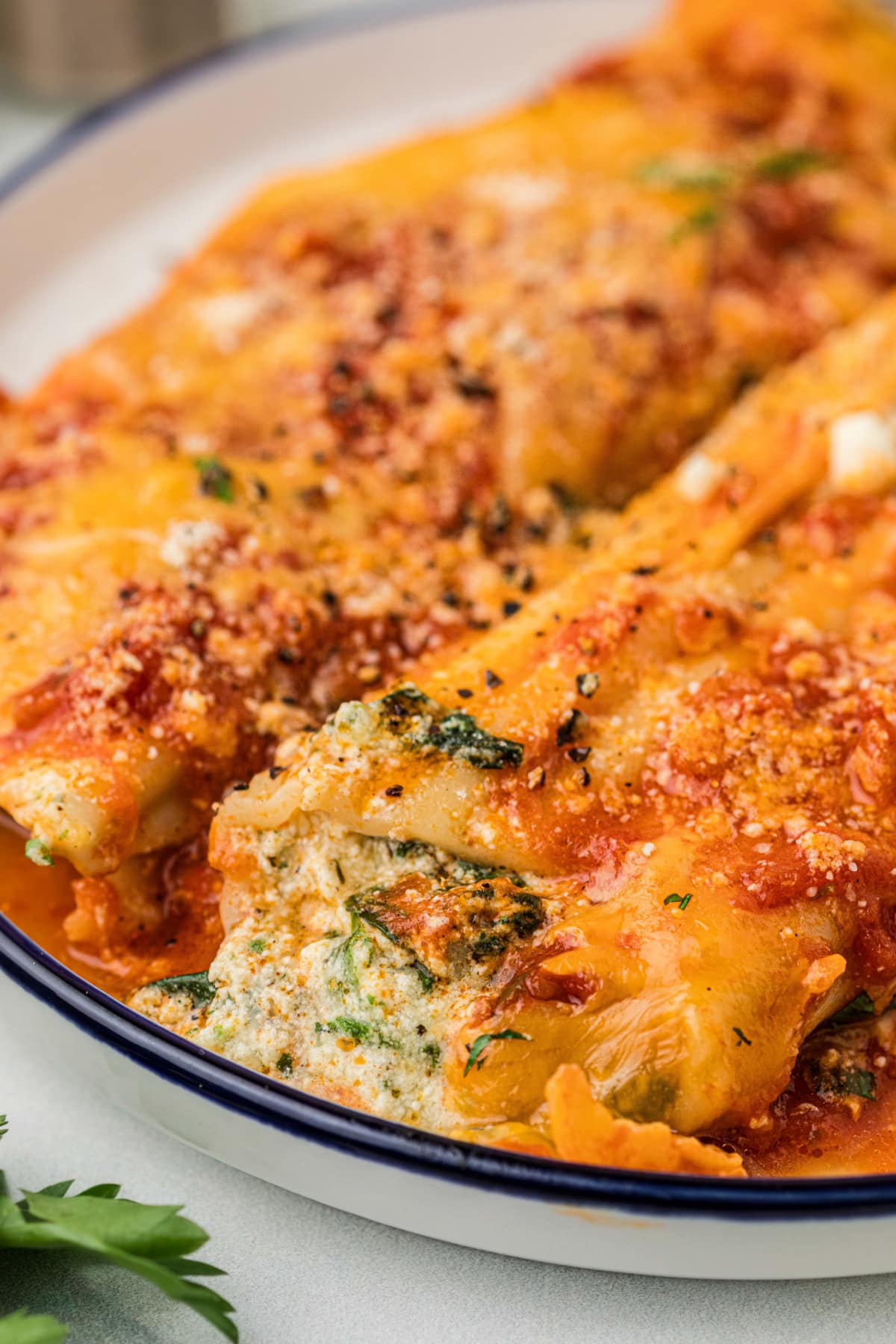 Close-up of ricotta and spinach manicotti with marinara sauce and melted cheddar cheese