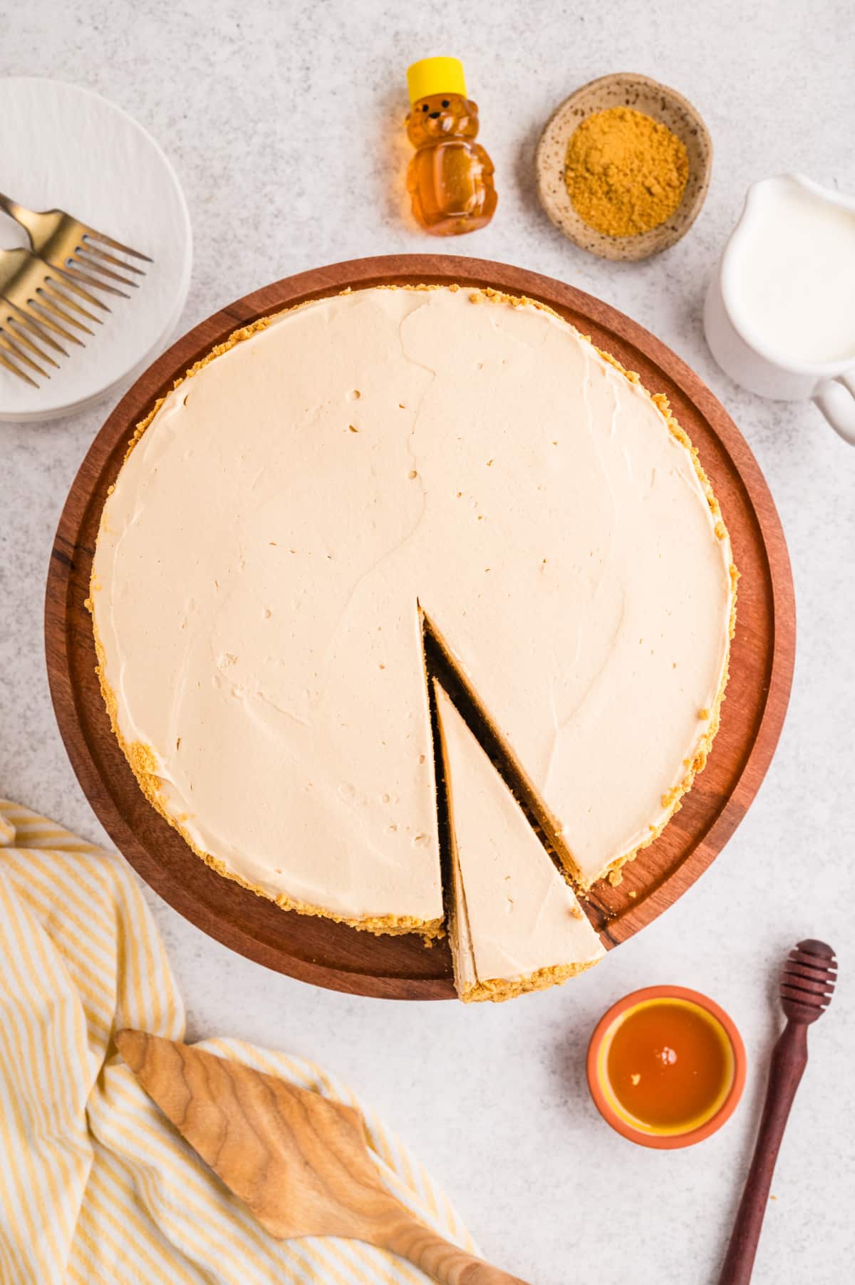 Top-down view of a layered honey cake with a single slice removed, showing the smooth frosted top and thin cake layers.